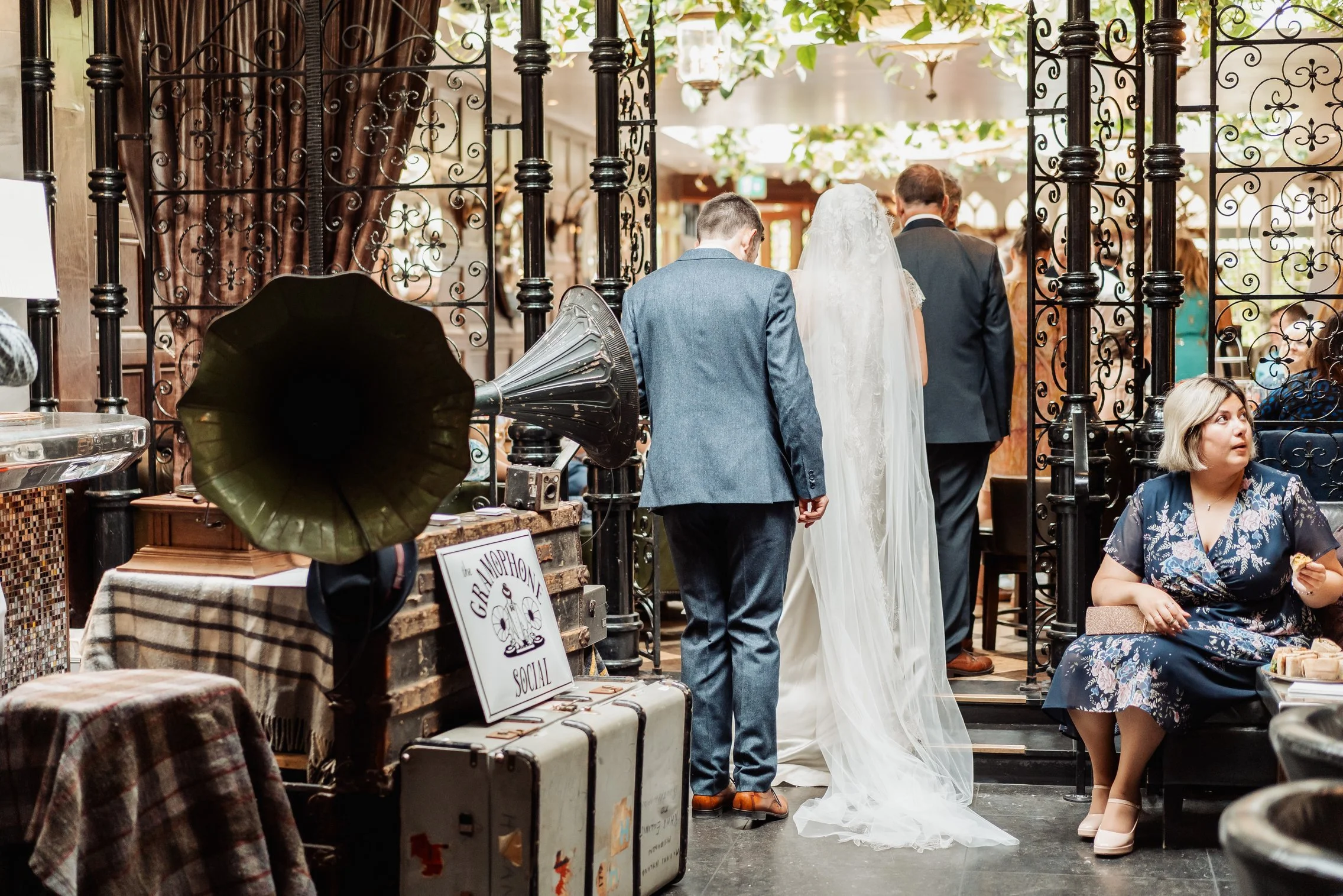 Wedding guests enjoying drinks and vintage gramophone music in a reception room.