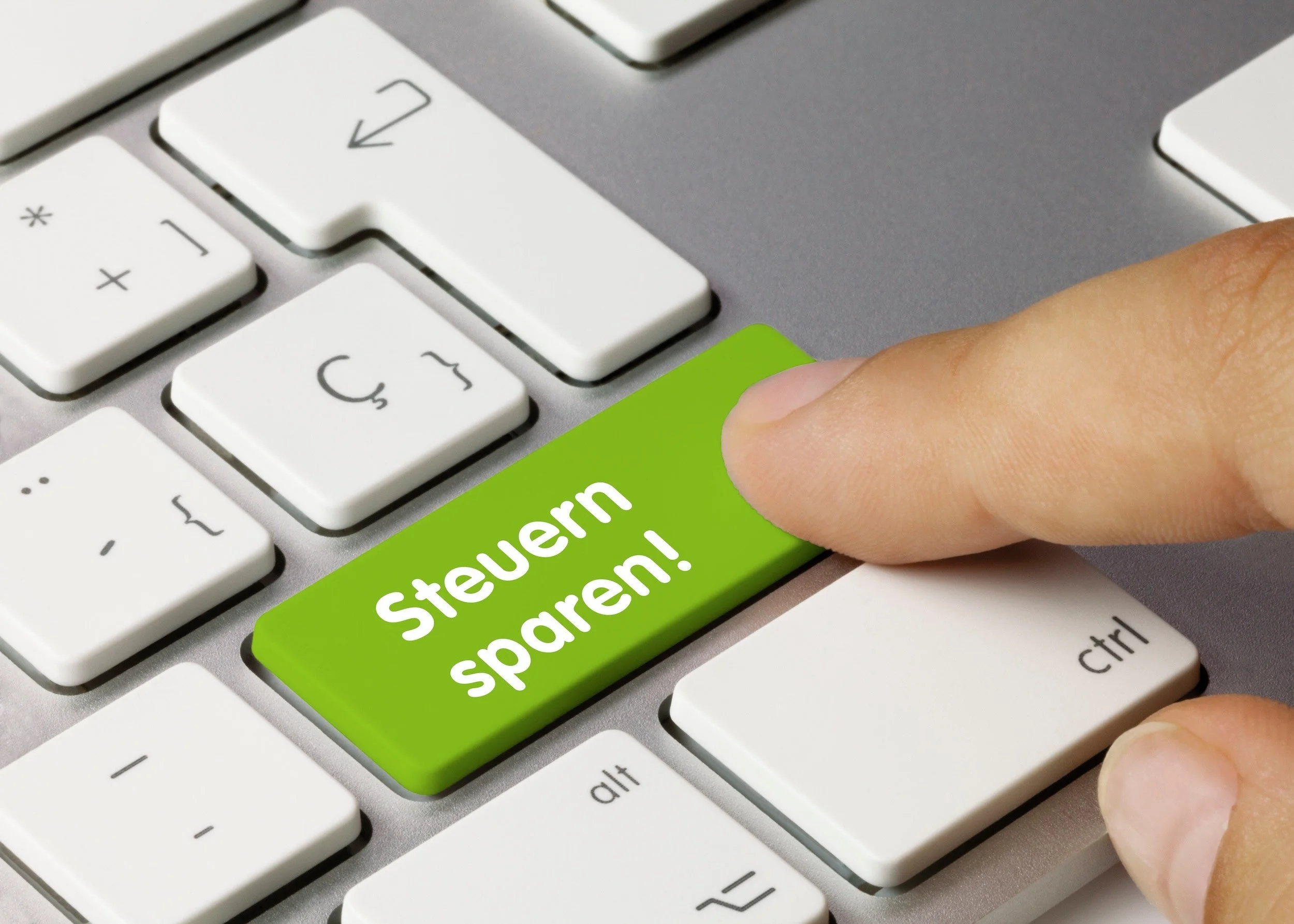 Ein Finger drückt auf eine Computertastatur-Taste mit der Aufschrift „Steuern sparen".