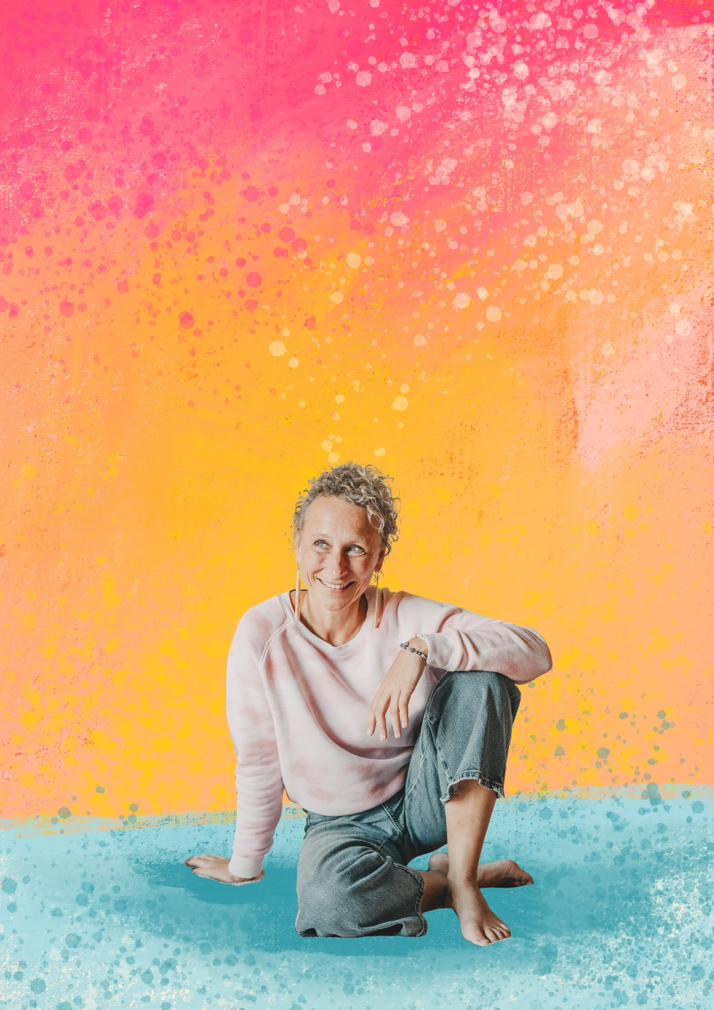 Eine lächelnde Frau sitzt auf dem Boden vor einem bunten, abstrakten Hintergrund in Pink, Orange und Blau.