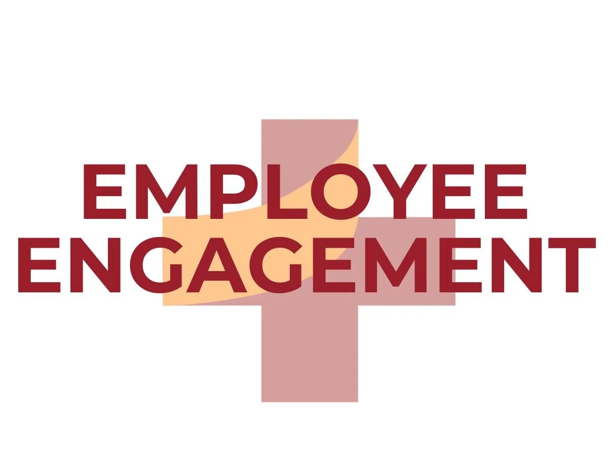 Graphic with the phrase ‘Employee Engagement’ in bold maroon text centered on an orange and maroon plus-sign symbol, symbolizing energy, motivation, and connection.