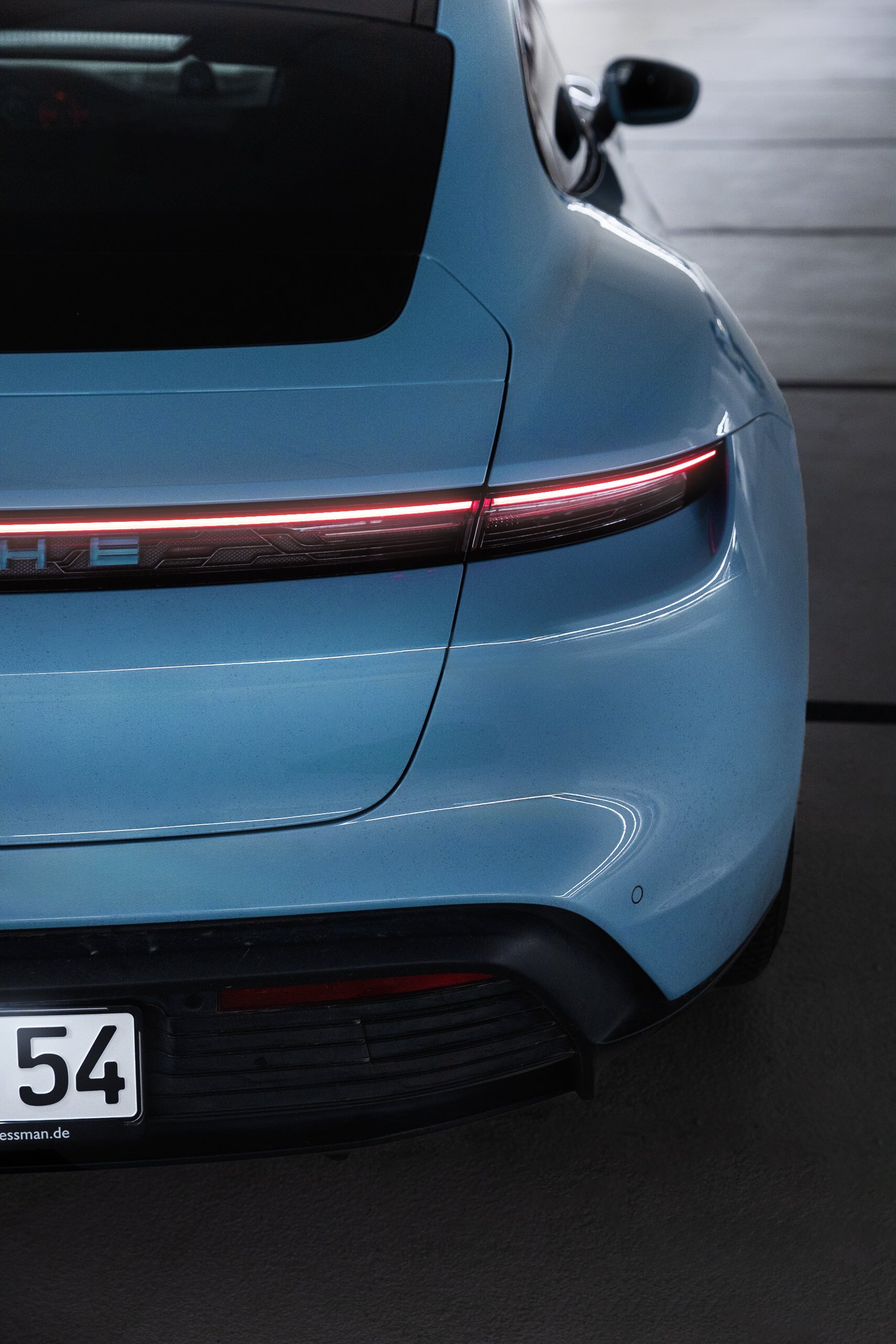 Nahaufnahme des Heckendes eines blauen Autos, zeigt LED-Heckleuchten und Teil des Nummernschilds.