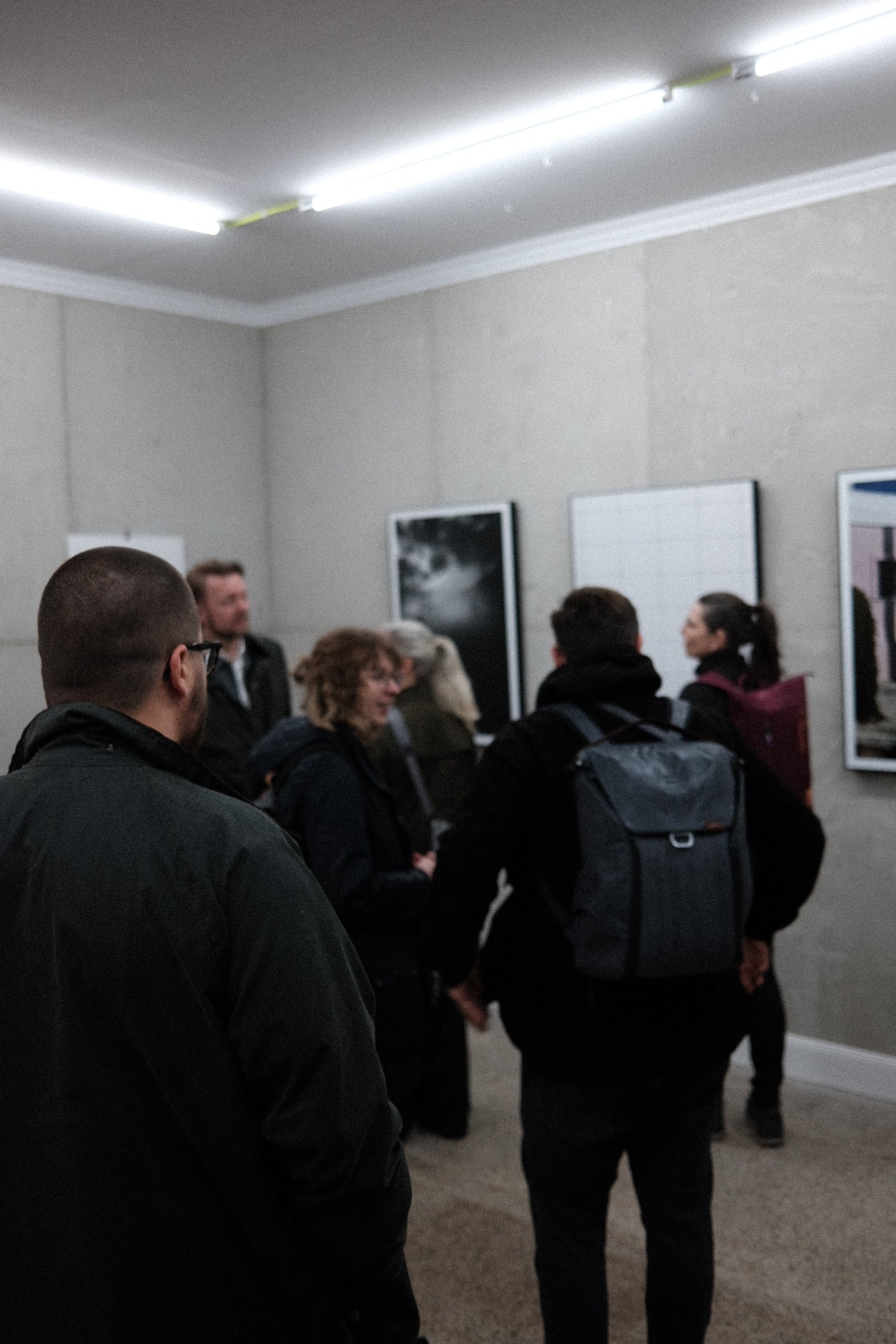 Menschen in einer Galerie betrachten Kunstwerke an der Wand.