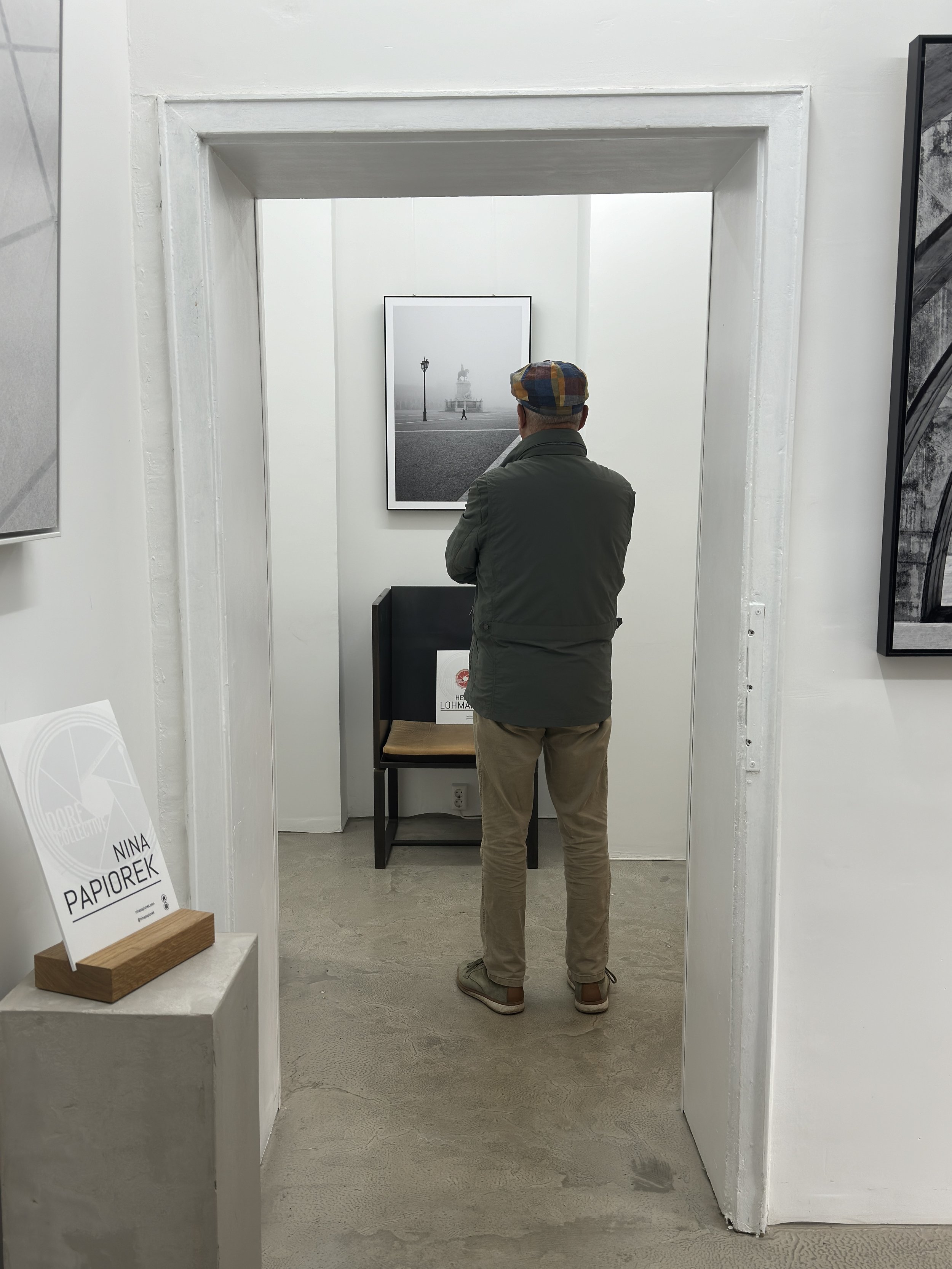 Ein Mann mit Kappe betrachtet ein Schwarz-Weiß-Foto in einem Ausstellungsraum.