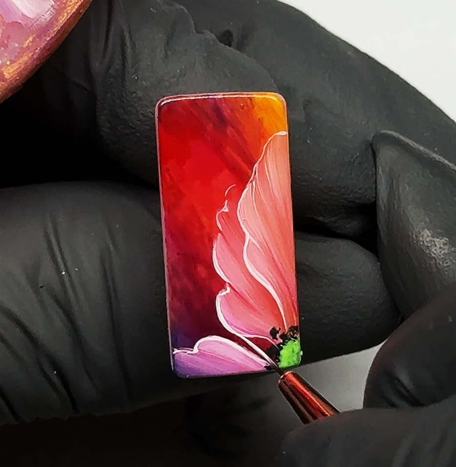 Flor camaleón pintada a mano sobre superficie cuadrada tamaño uña con combinación de colores profundos rojo, amarillo y magenta. Diseño de nail art artístico elaborado con técnica one stroke y detalles luminosos para lograr pétalos intensos y sofisti