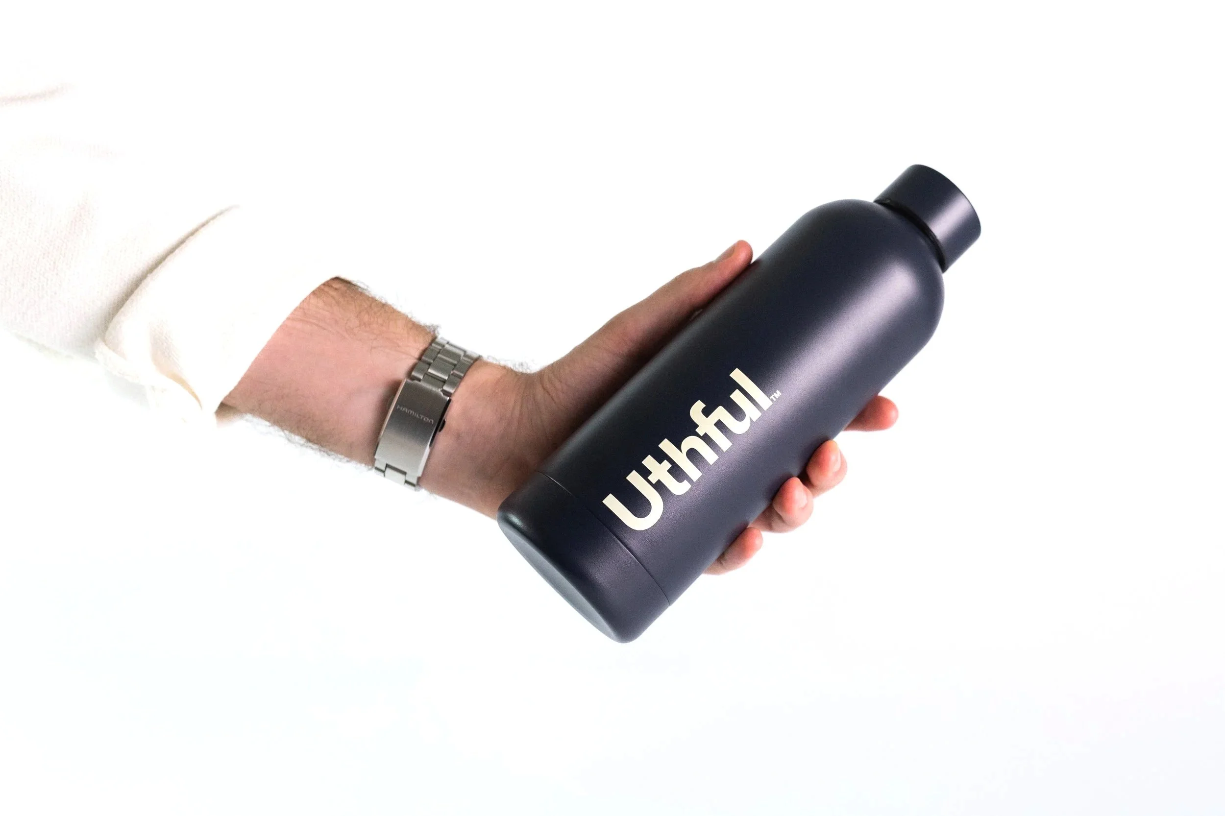 A person in a white shirt holding a black stainless steel water bottle with the brand name 'Uthful' printed on it, against a white background.