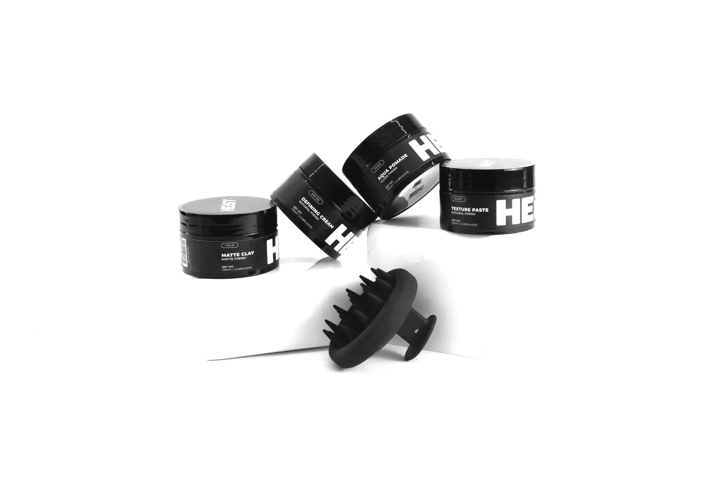 Heist hair care brand image of four black jars of hair styling products and a black hair pick with widely spaced teeth on a white background.
