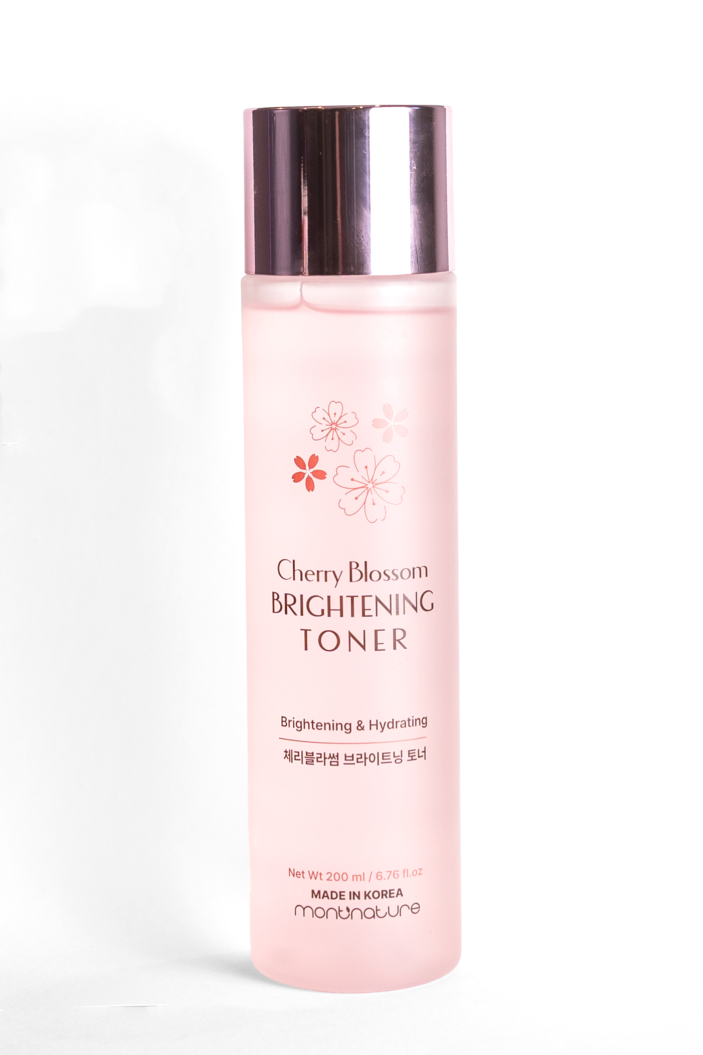 A pink bottle of Cherry Blossom Brightening Toner with a silver cap, decorated with cherry blossom illustrations, labeled as a hydrating and brightening skincare product made in Korea.