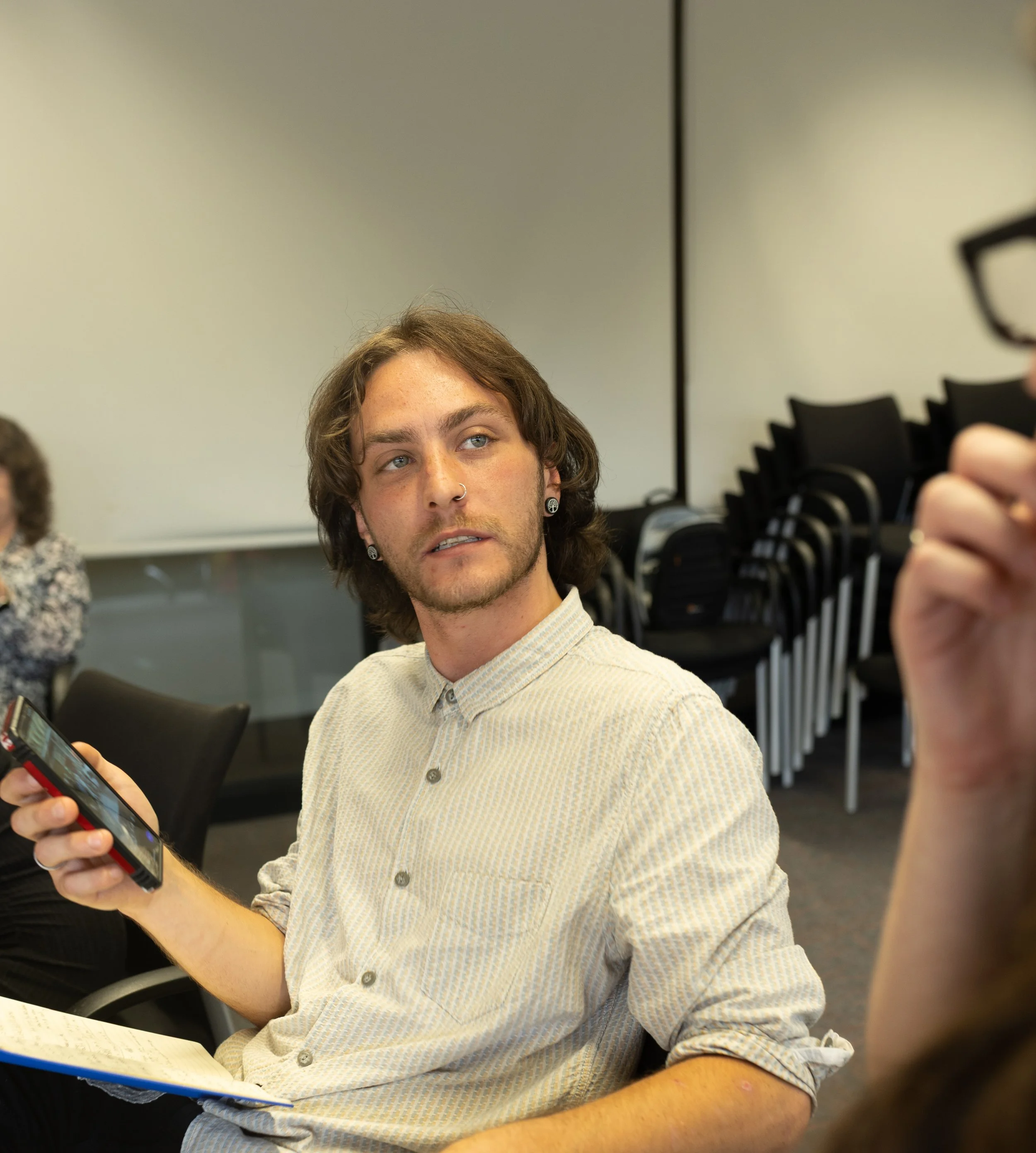 Authentic personal brand photography of an entrepreneur holding a phone in a meeting or professional setting.