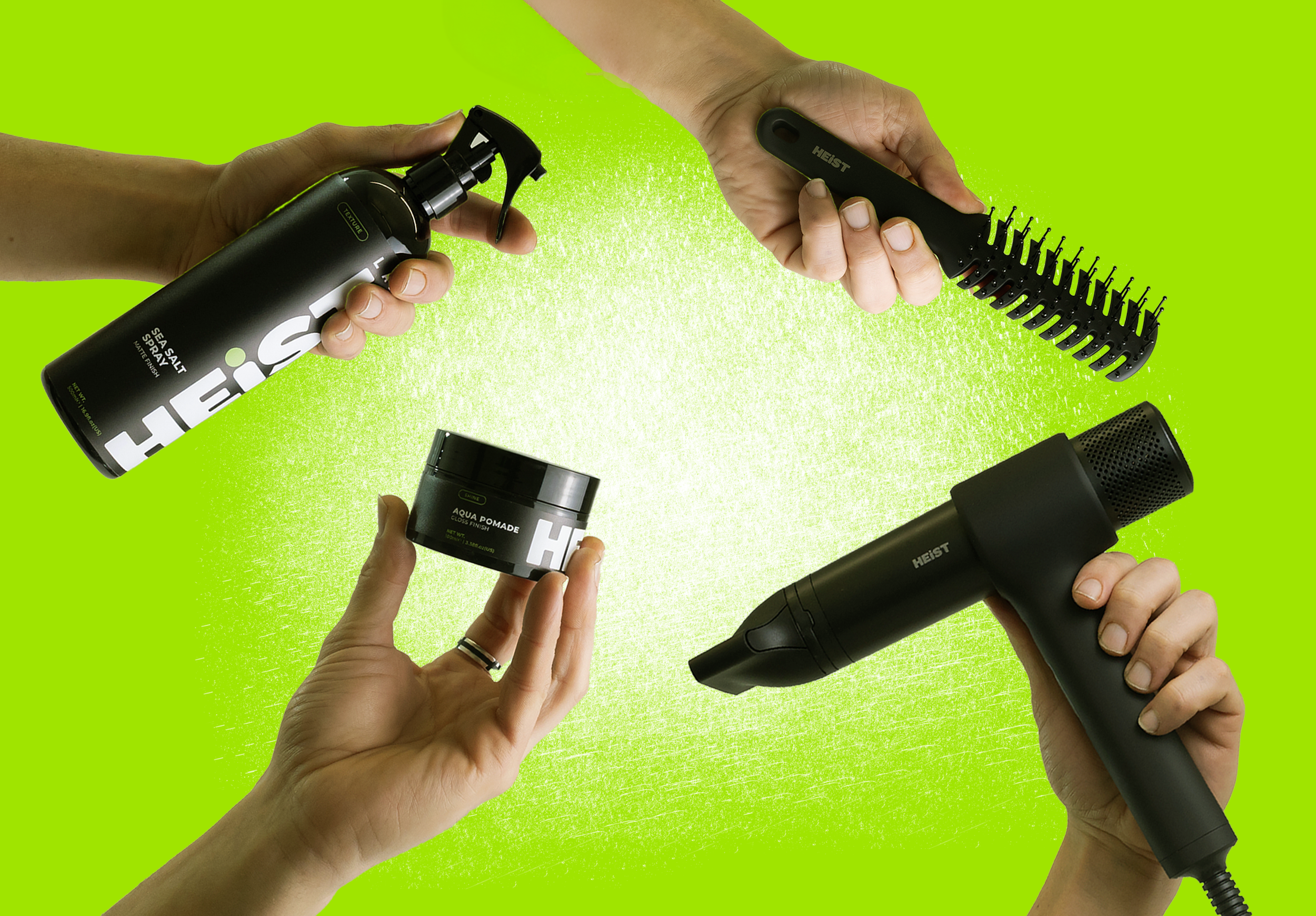 Hands holding various hairstyling tools including a spray bottle, a hair pomade jar, a hairbrush, a blow dryer, and a round hairbrush against a green background.