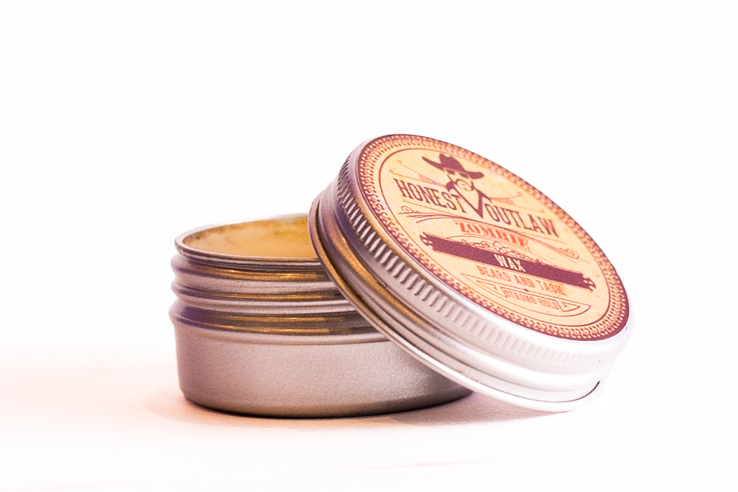 Ecommerce product photo with an open tin of Honest Outlaw beard and moustache wax with a red and tan label.
