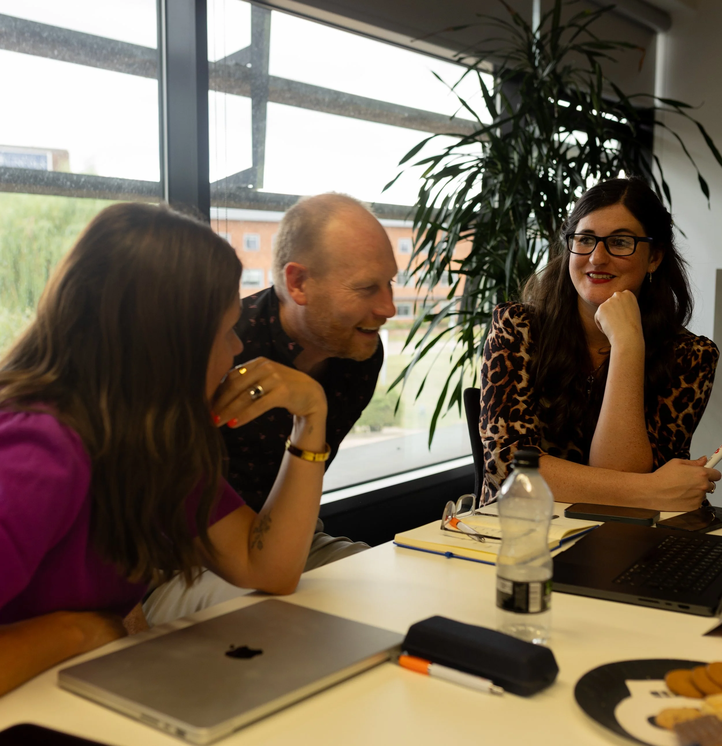 Unposed lifestyle photography showing two people engaged in a focused, candid conversation at a business meeting.