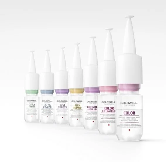 Collection of Goldwell hair coloring bottles with various label colors and product names.