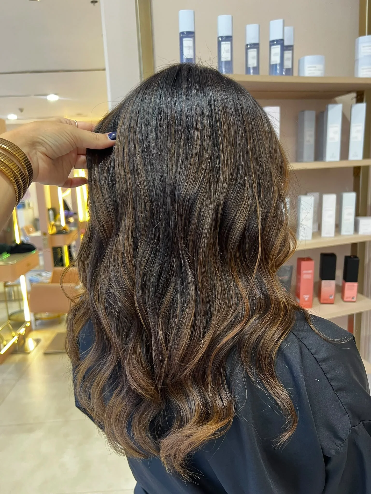  long, wavy hair that transitions from dark brown at the roots to lighter caramel or honey blonde at the ends