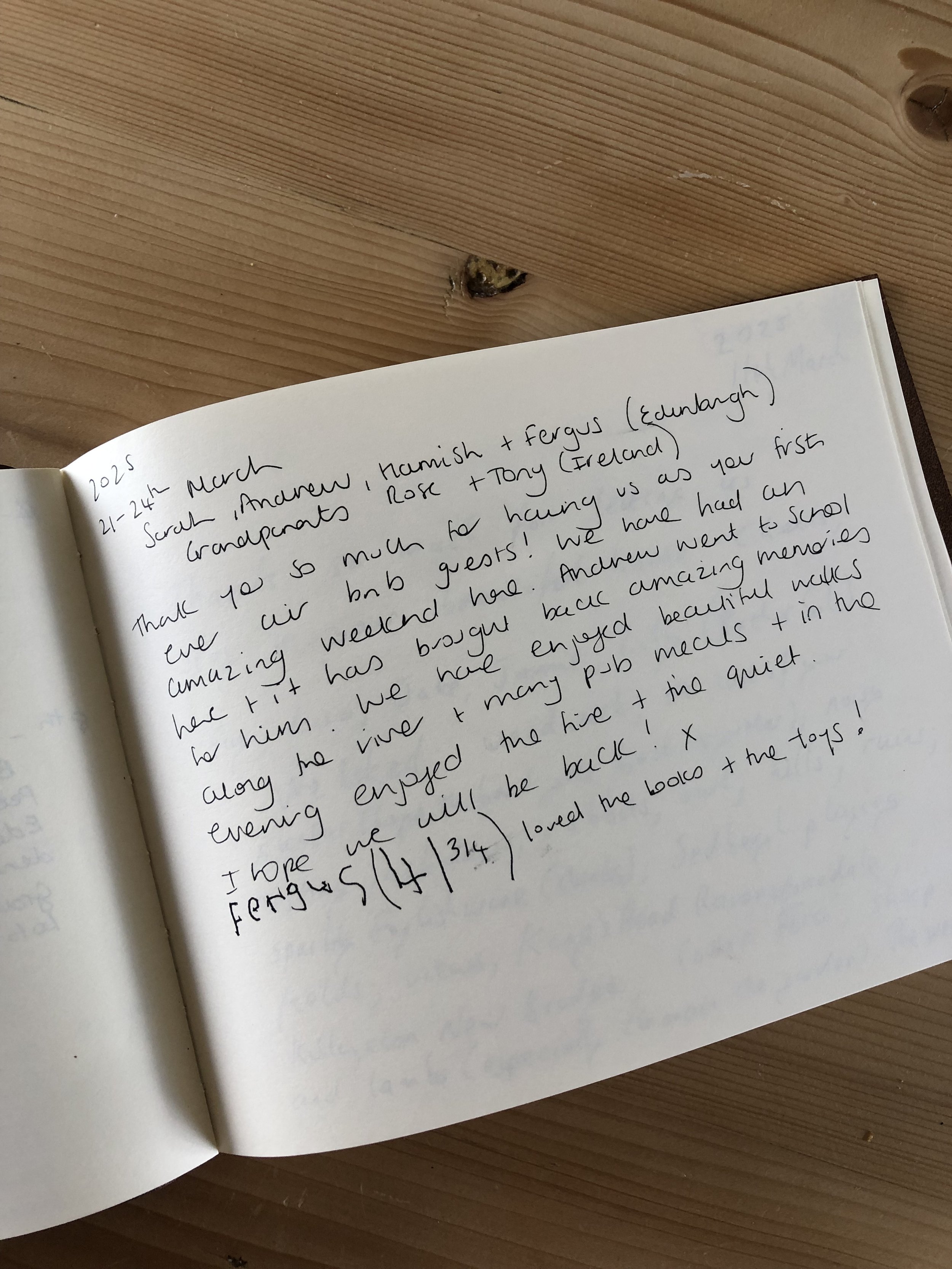 A handwritten letter in a notebook with a wooden surface background.