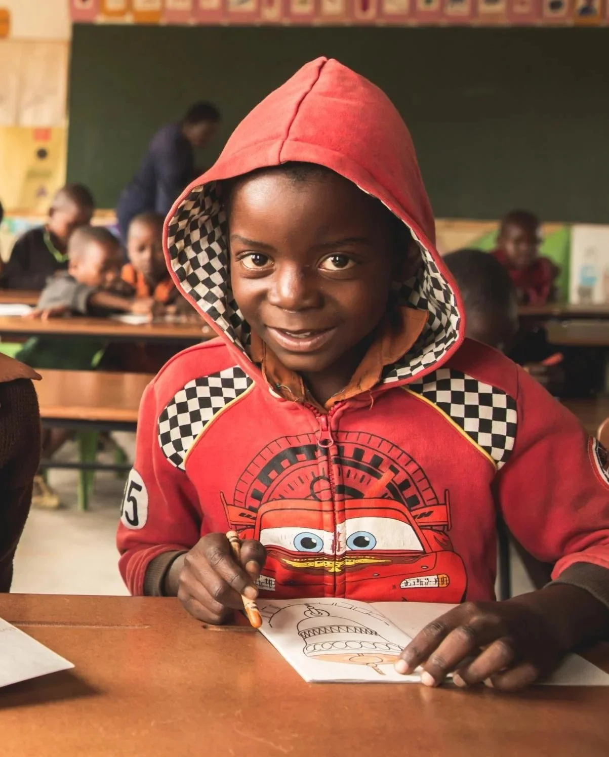 A young boy called Ariko wearing red and working in a classroom