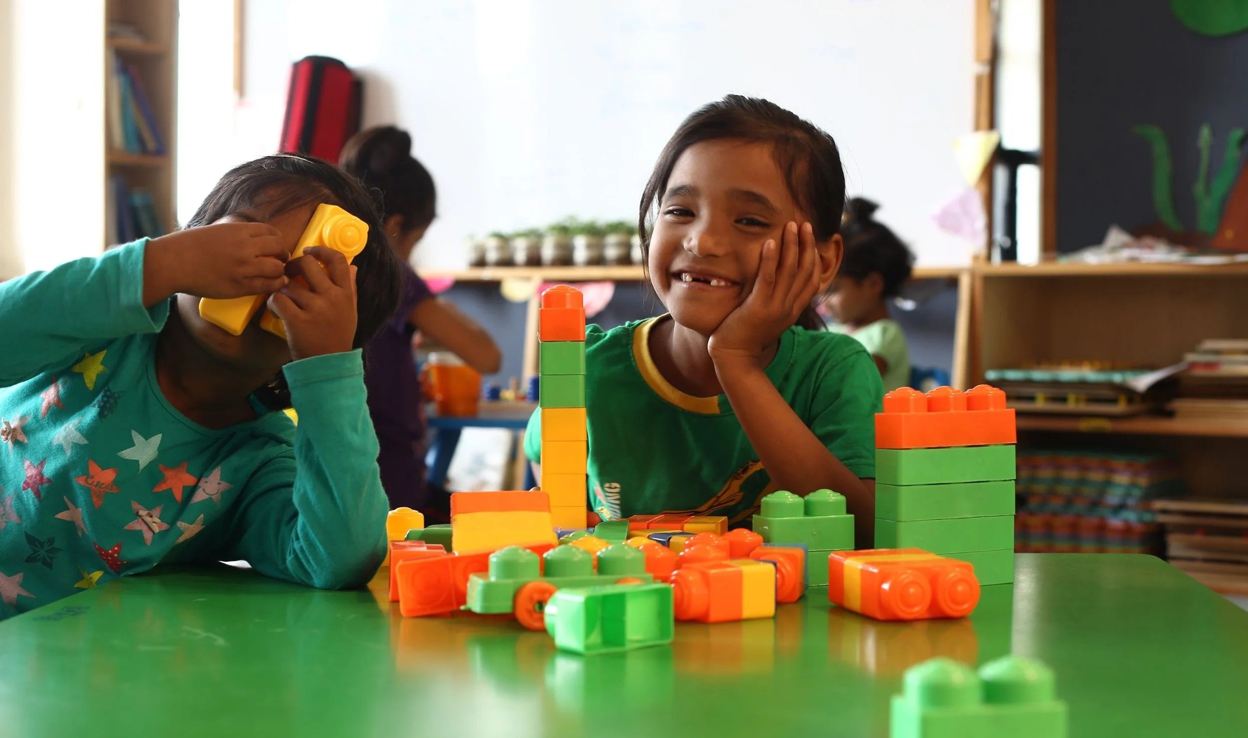 Quote from Reverend Devaraj about rescuing children alongside photo of two young girls playing in a classroom