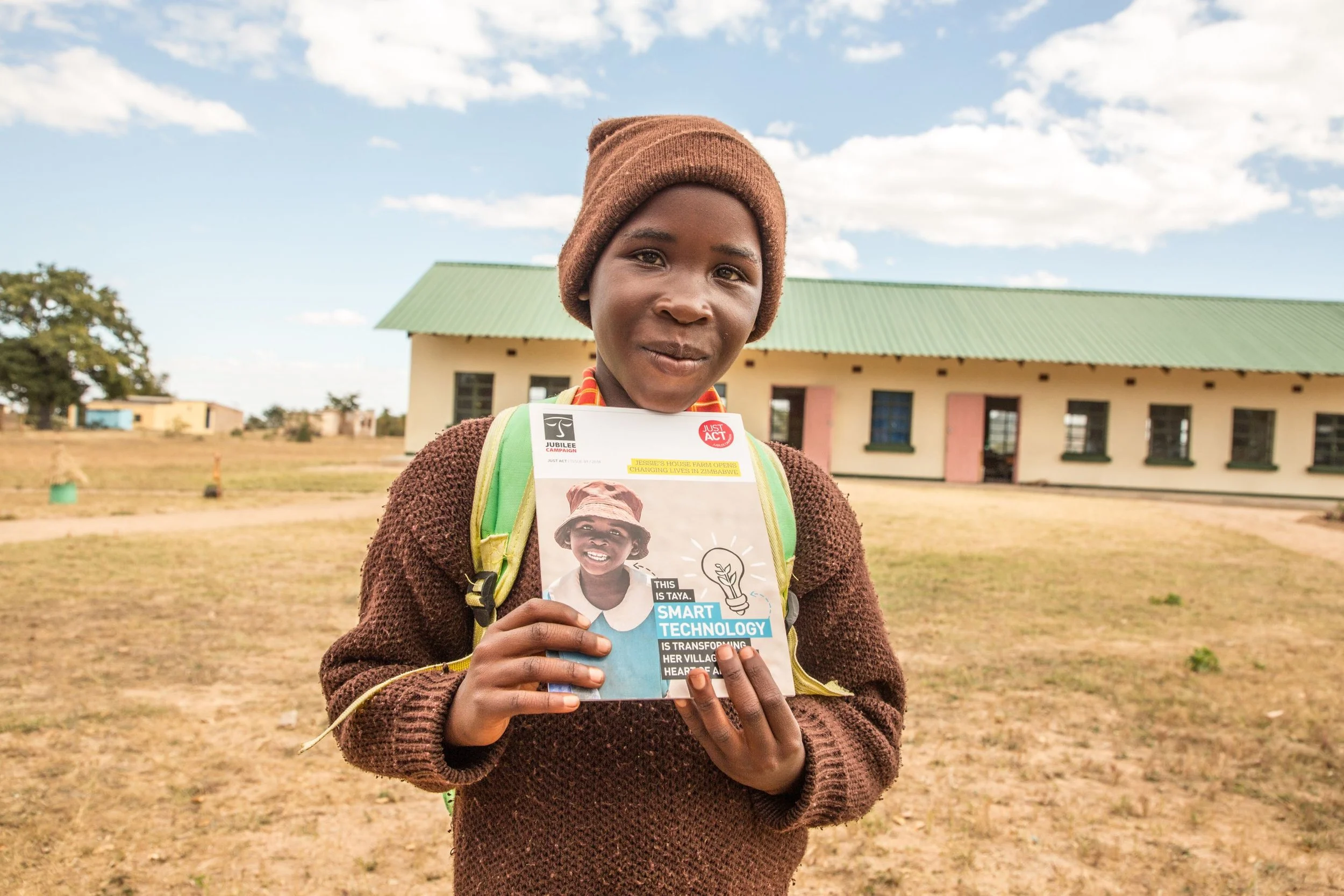 Taya outside Jessie's House holding a booklet featuring her photo