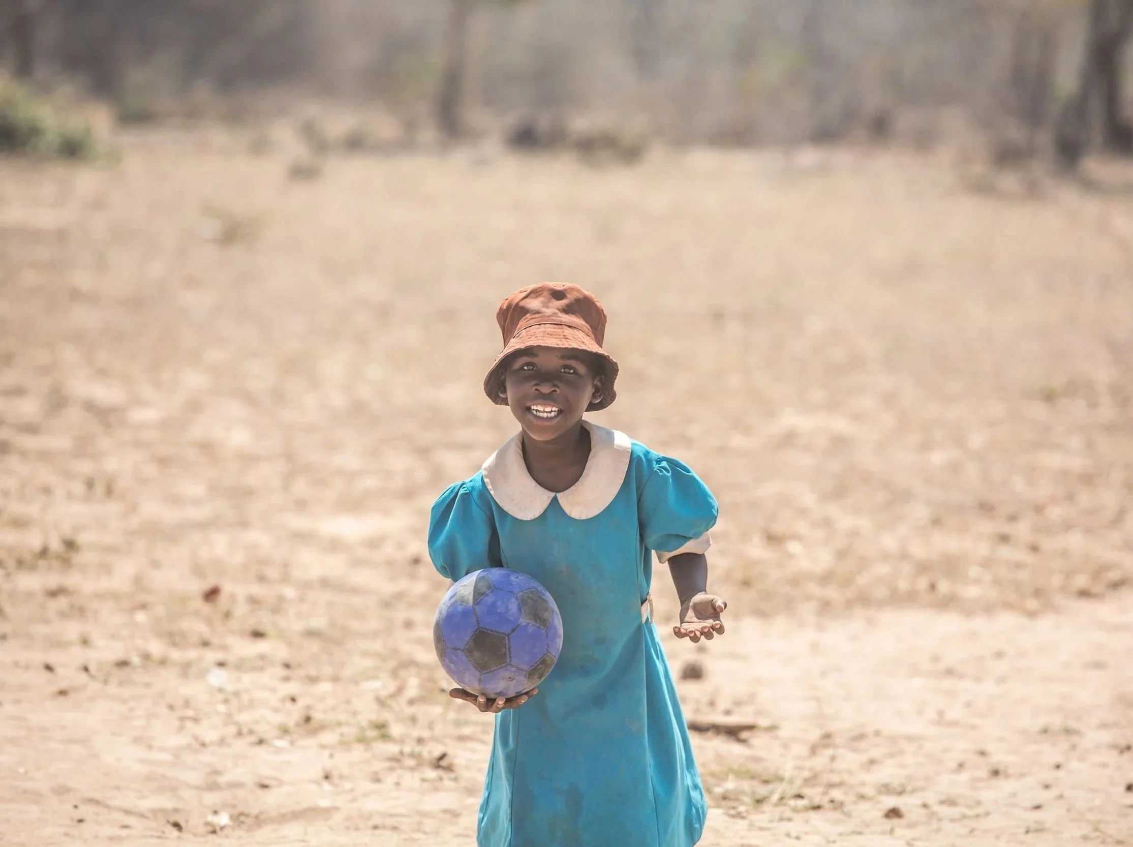 Taya playing with a blue ball and smiling