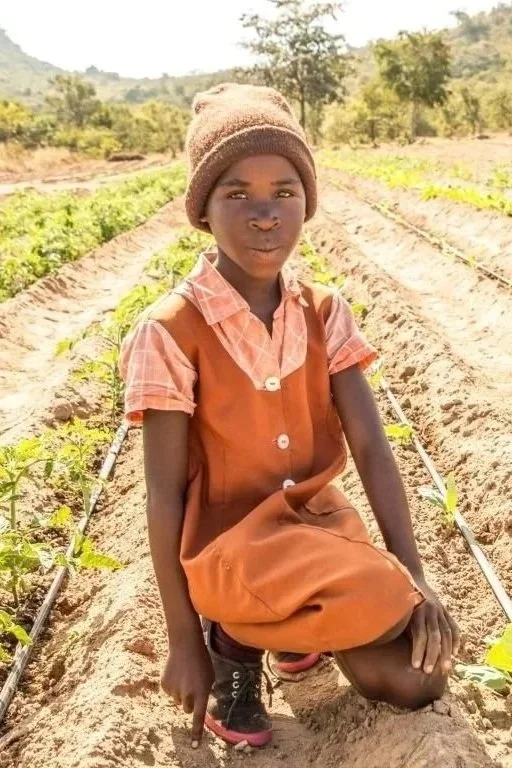 Taya at Jessie's House Farm, drip irrigation can be seen watering crops behind her