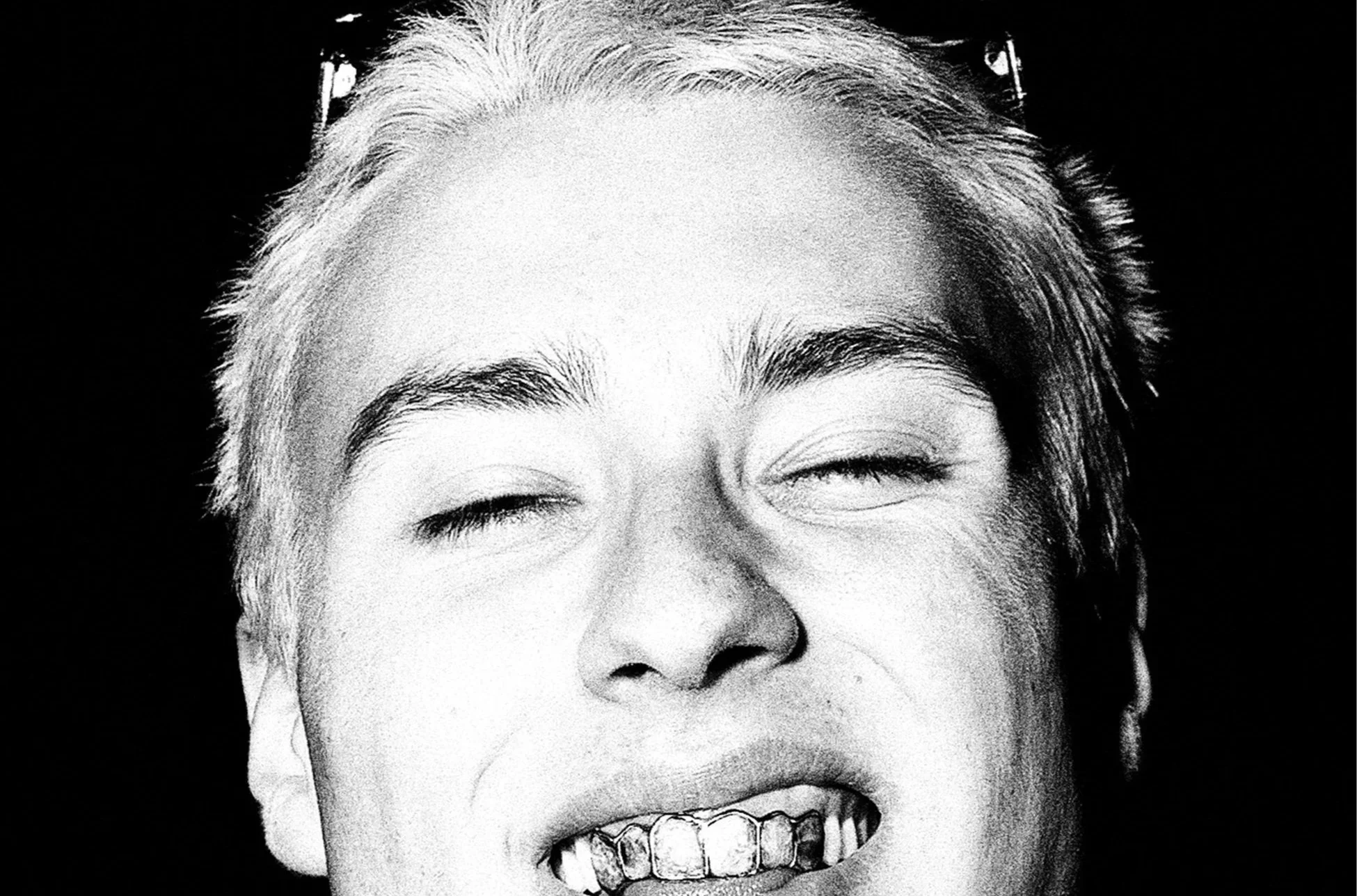 Black and white close-up photograph of a person's face, smiling with eyes closed, showing teeth. Fashion and portrait photographer in Barcelona.