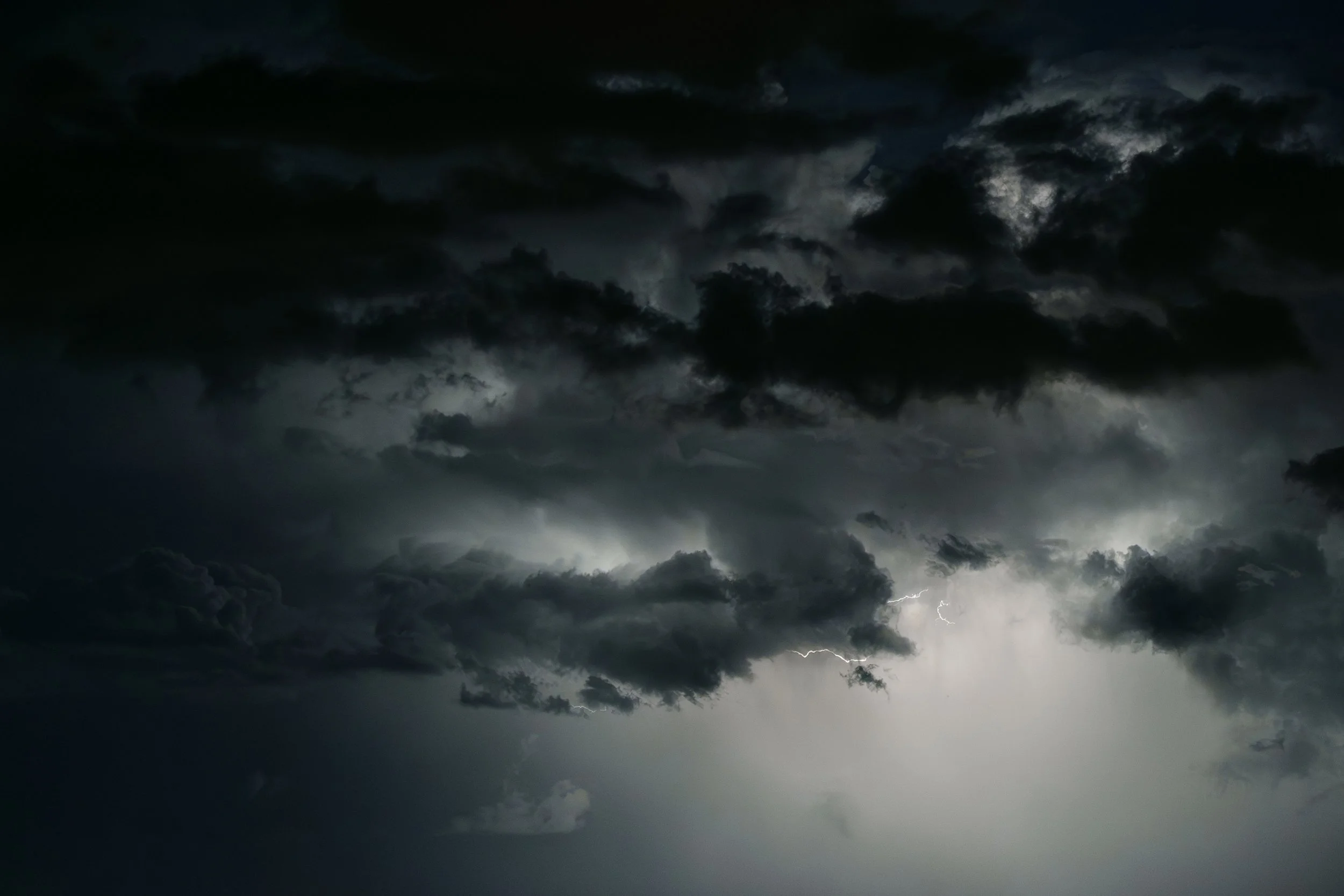 Dark stormy clouds with lightning flashes in the sky.