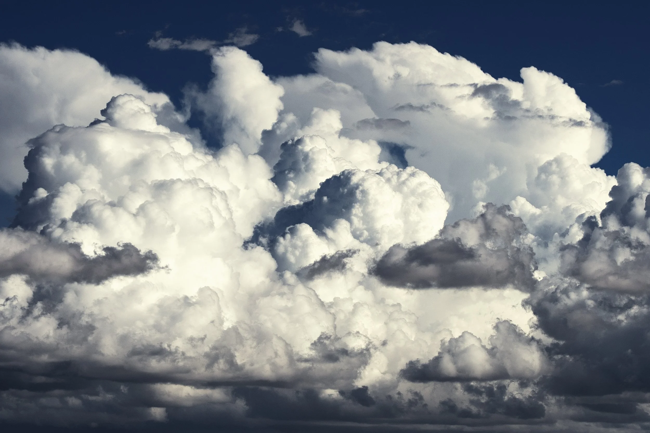 A sky filled with large, fluffy white and gray cumulonimbus clouds.