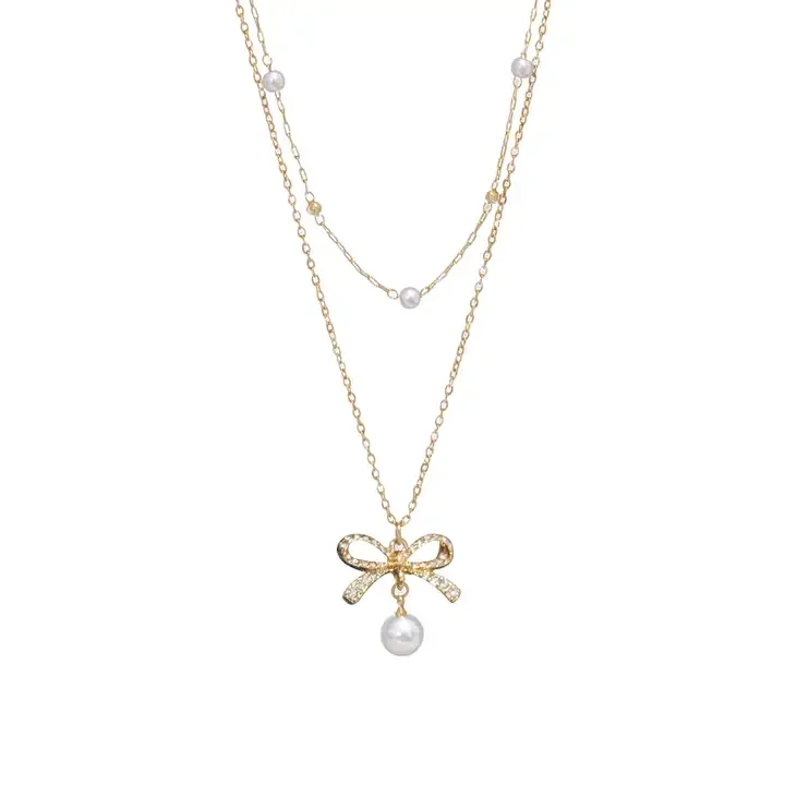 Three layered gold necklaces with pearl accents and a bow-shaped pendant with a pearl drop.