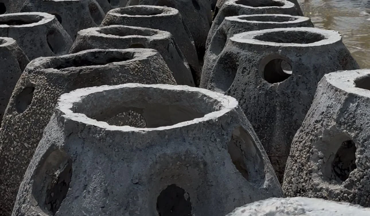 Multiple concrete tetrapods arranged near a body of water, used for coastal erosion protection.