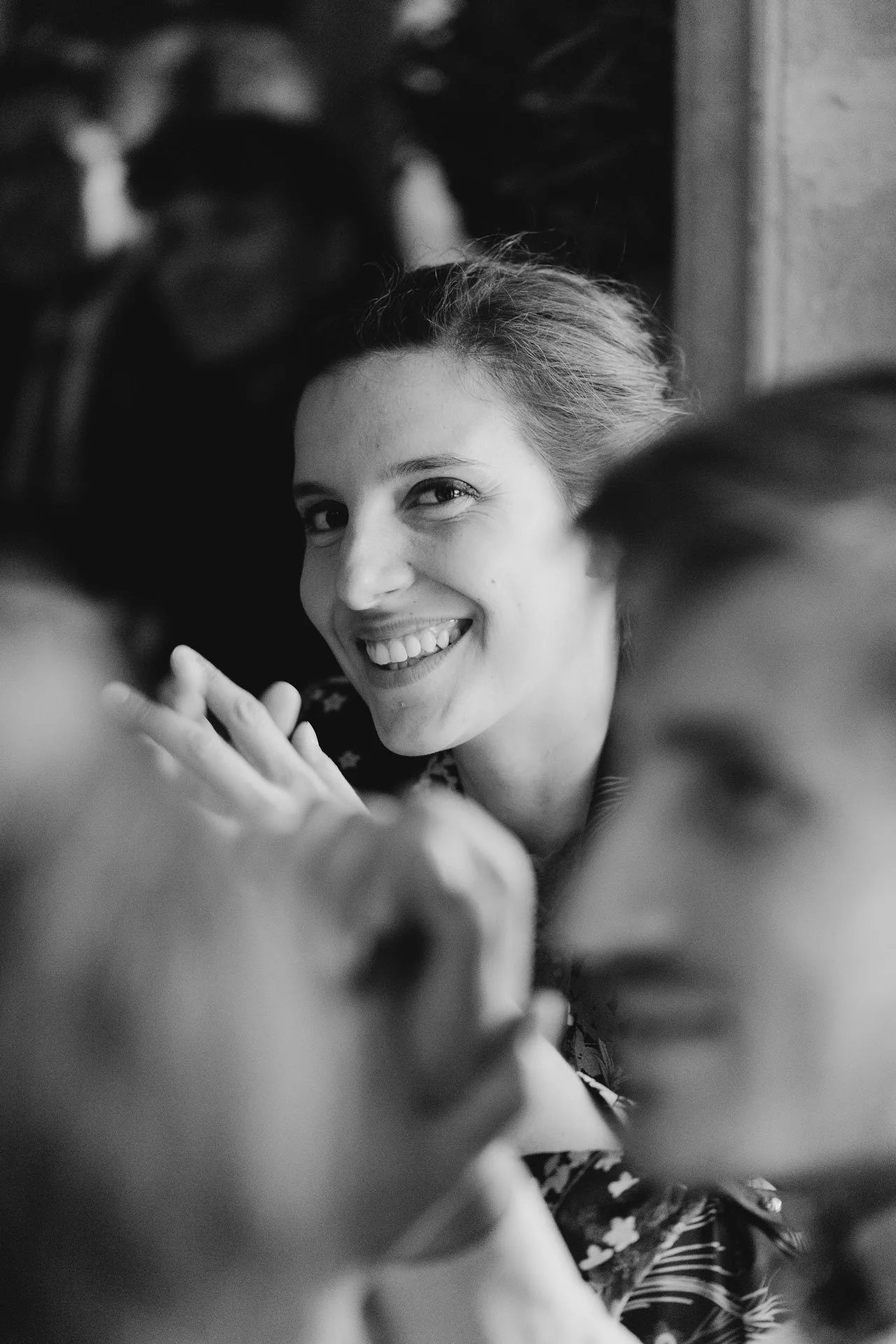 Photographe de reportage mariage, portrait en noir et blanc d'une femme souriante qui regarde vers l'objectif, lors d'un diner
