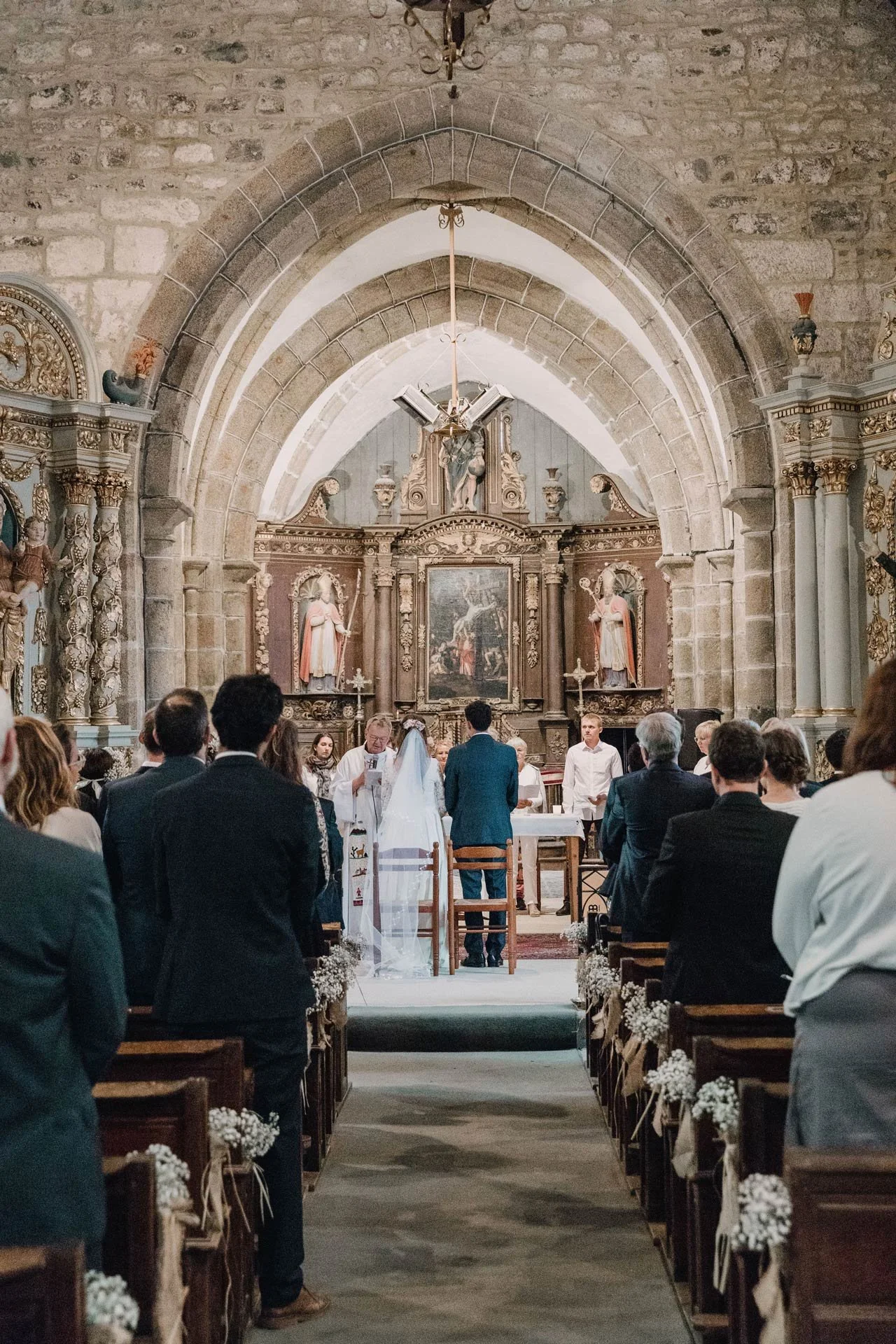 Photographe de mariage en Normandie, scène intimiste dans une église où le couple se tient devant le prêtre