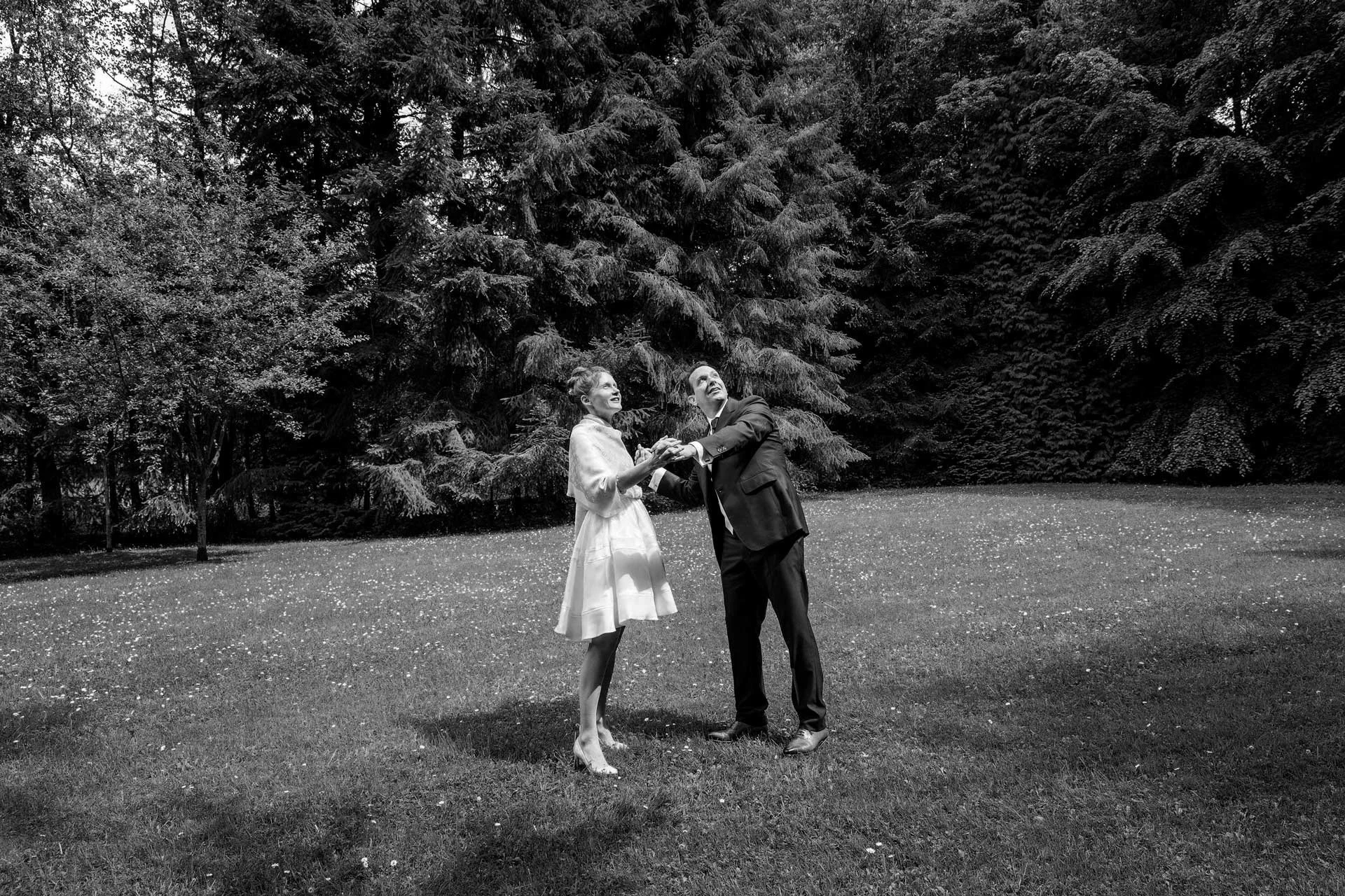 Un couple dansant dans un parc, en noir et blanc, entouré d'arbres.