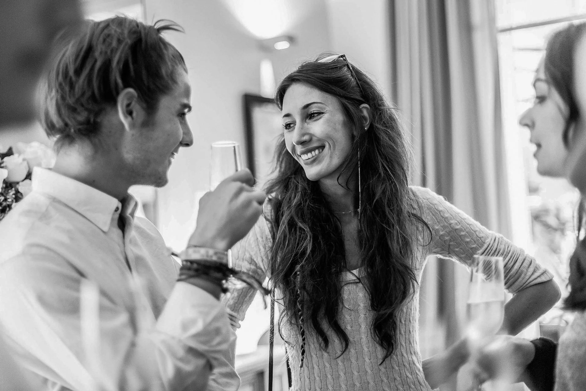 Groupe de trois personnes souriantes et parlant lors d'un cocktail de mariage, en intérieur.