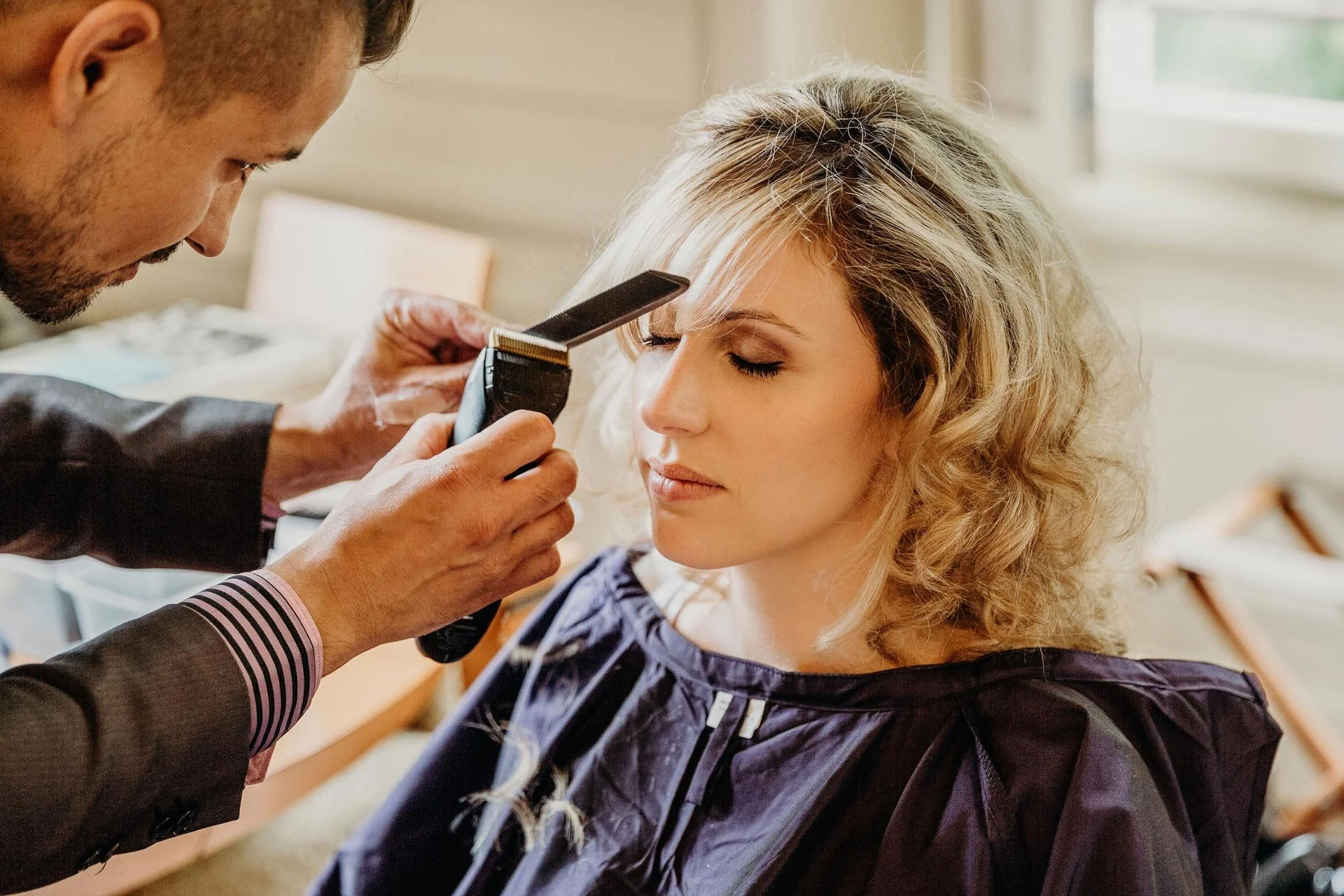 Un coiffeur coupe les cheveux d'une femme lors des préparatifs de mariage.
