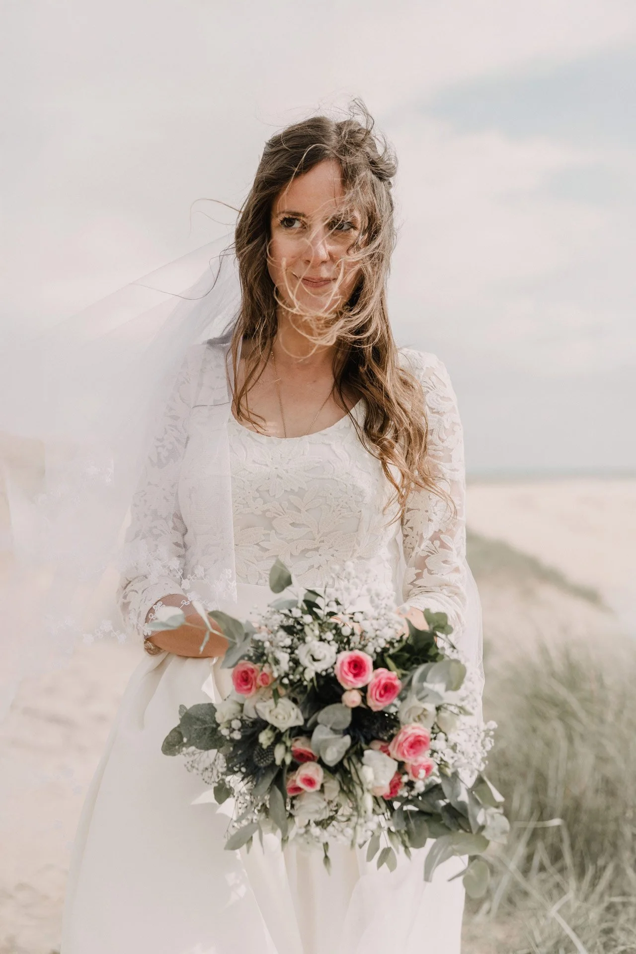 Photographe de mariage en Normandie, portrait de la mariée avec un bouquet de fleurs sur la plage