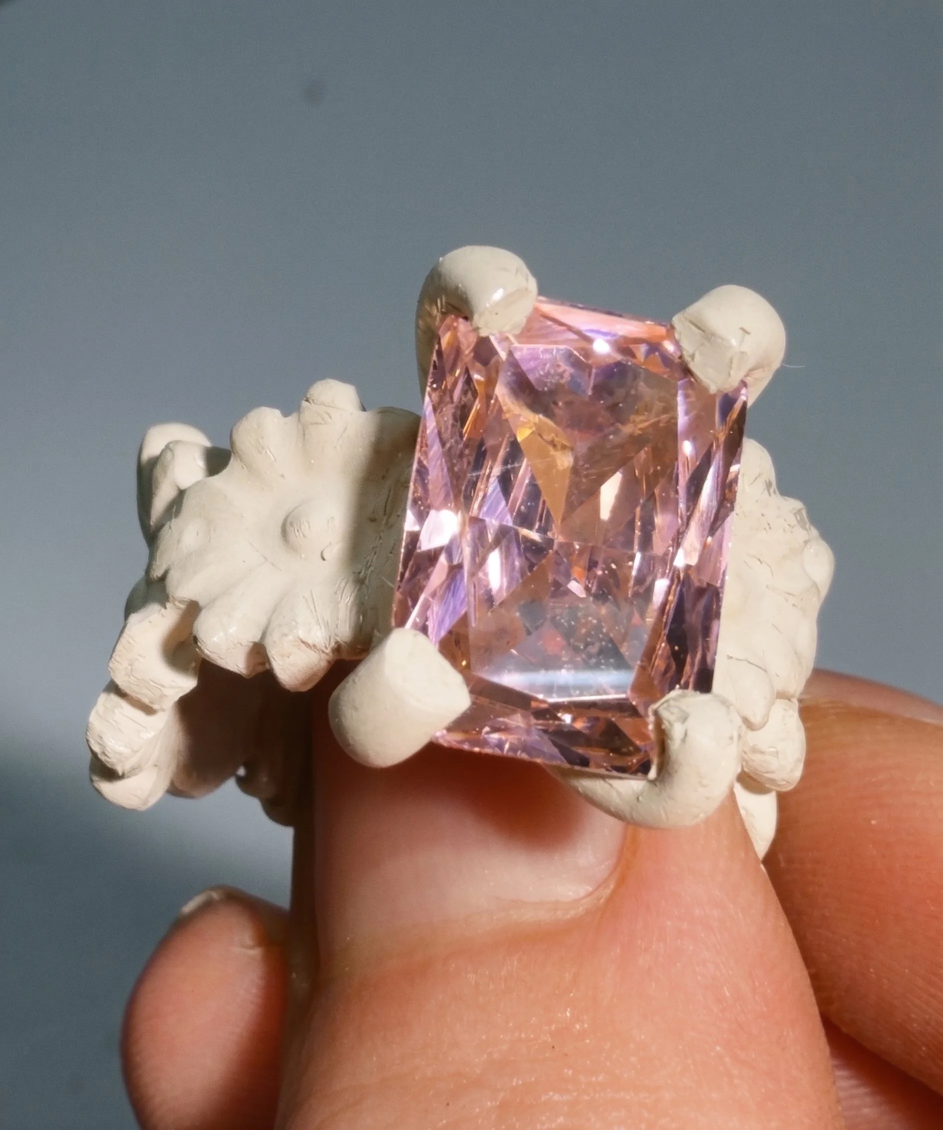 Unfired metal clay ring with a pink gemstone, before kiln firing