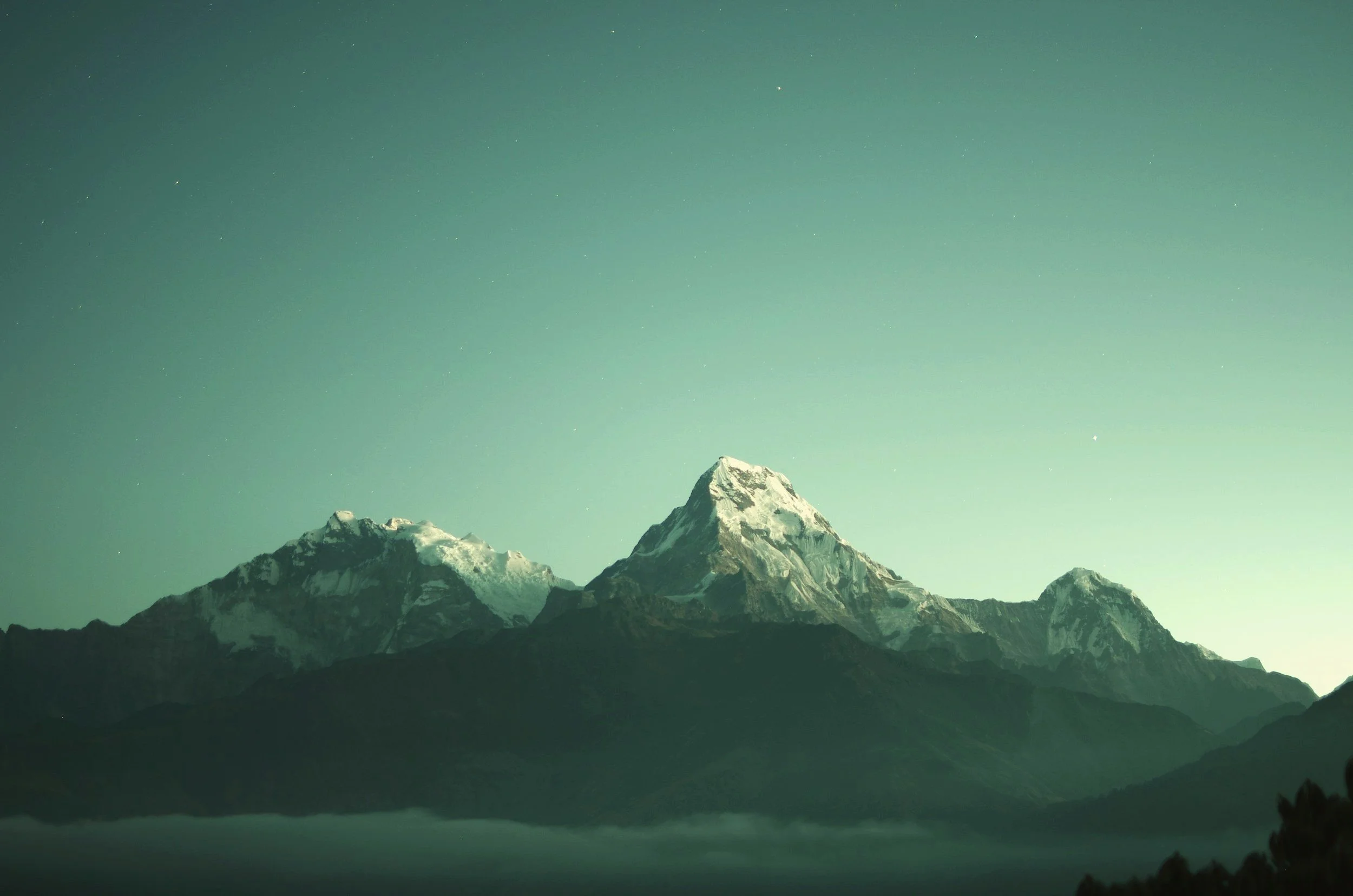 Snow-capped mountains at dusk with a clear sky and faint stars.