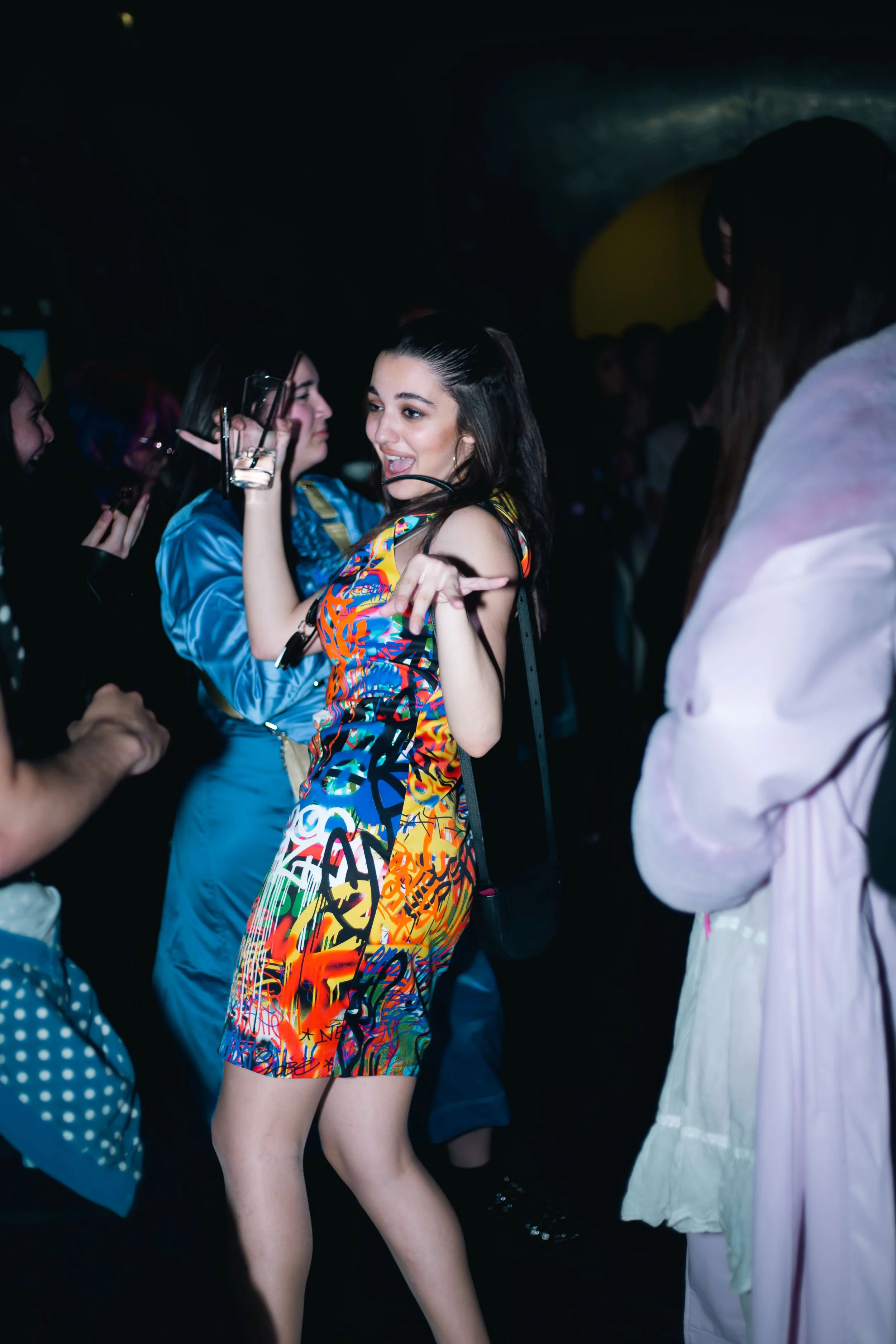 Fête avec des jeunes adultes dansant et socialisant dans une ambiance sombre, plusieurs personnes visibles