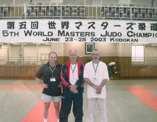 Three men standing on a judo mat at the 5th World Masters Judo Championship in Kodokan, June 23-28, 2003.