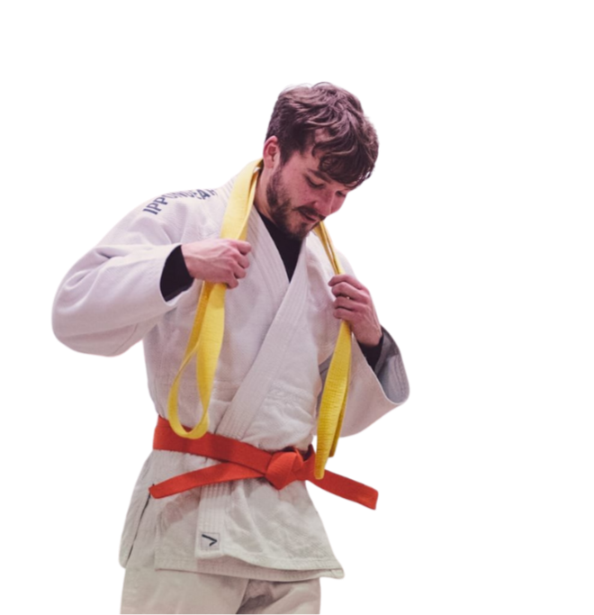 A man in a judo uniform with a yellow belt, adjusting his belt, on a plain background.
