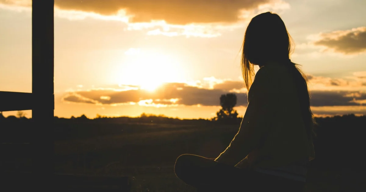 Persona en silencio meditando al atardecer, reflejando un proceso de autocuidado y cambio personal