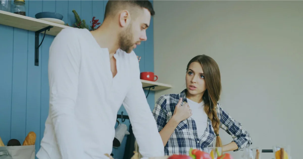 Pareja en tensión en la cocina, dinámica de conflicto cotidiano en pareja