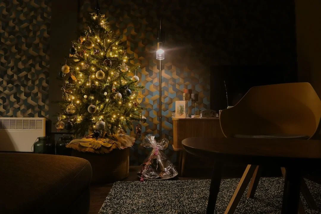 Árbol de Navidad iluminado en un salón tranquilo y en penumbra, símbolo de unas fiestas vividas con calma y cuidado emocional.