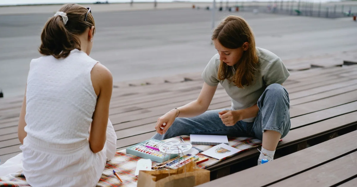 Madre conversando con su hija adolescente en la playa durante el verano en Barcelona