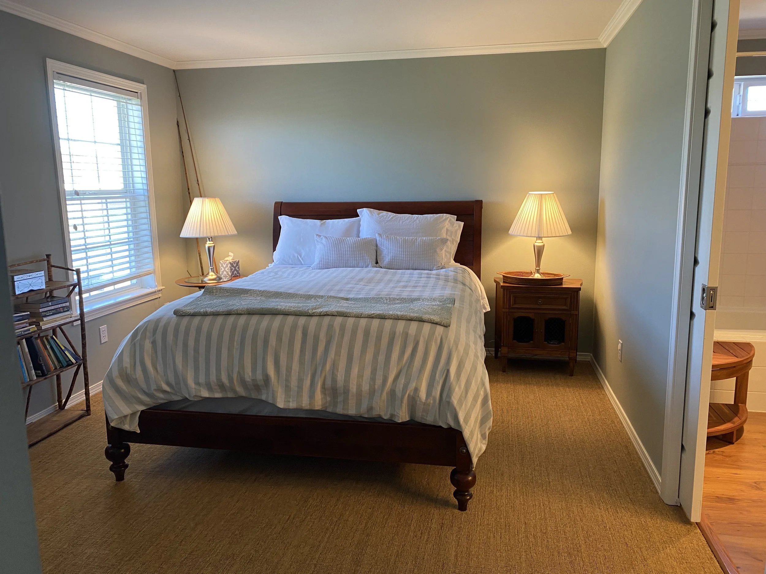 Bedroom with large bed, pale green walls, and lamps on either side of the bed