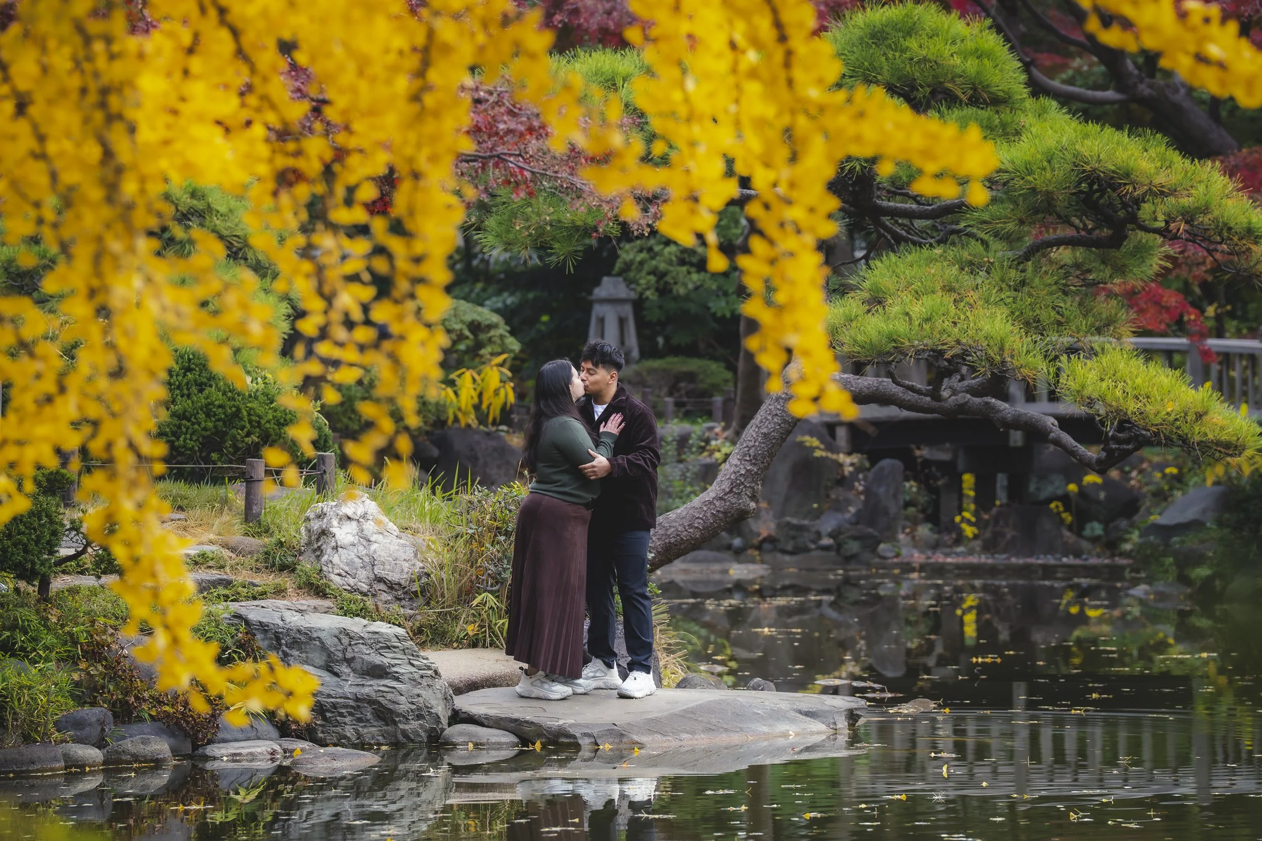 Couple enjoying a natural autumn photoshoot in Japan surrounded by colourful trees