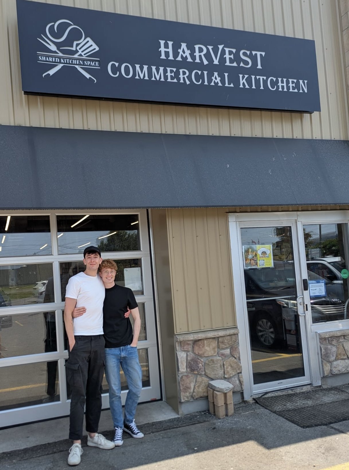 The owners of Thyme to Gather, Jesse and Ben, standing outside the Harvest Commercial Kitchen, a shared kitchen space, posing for a photo.