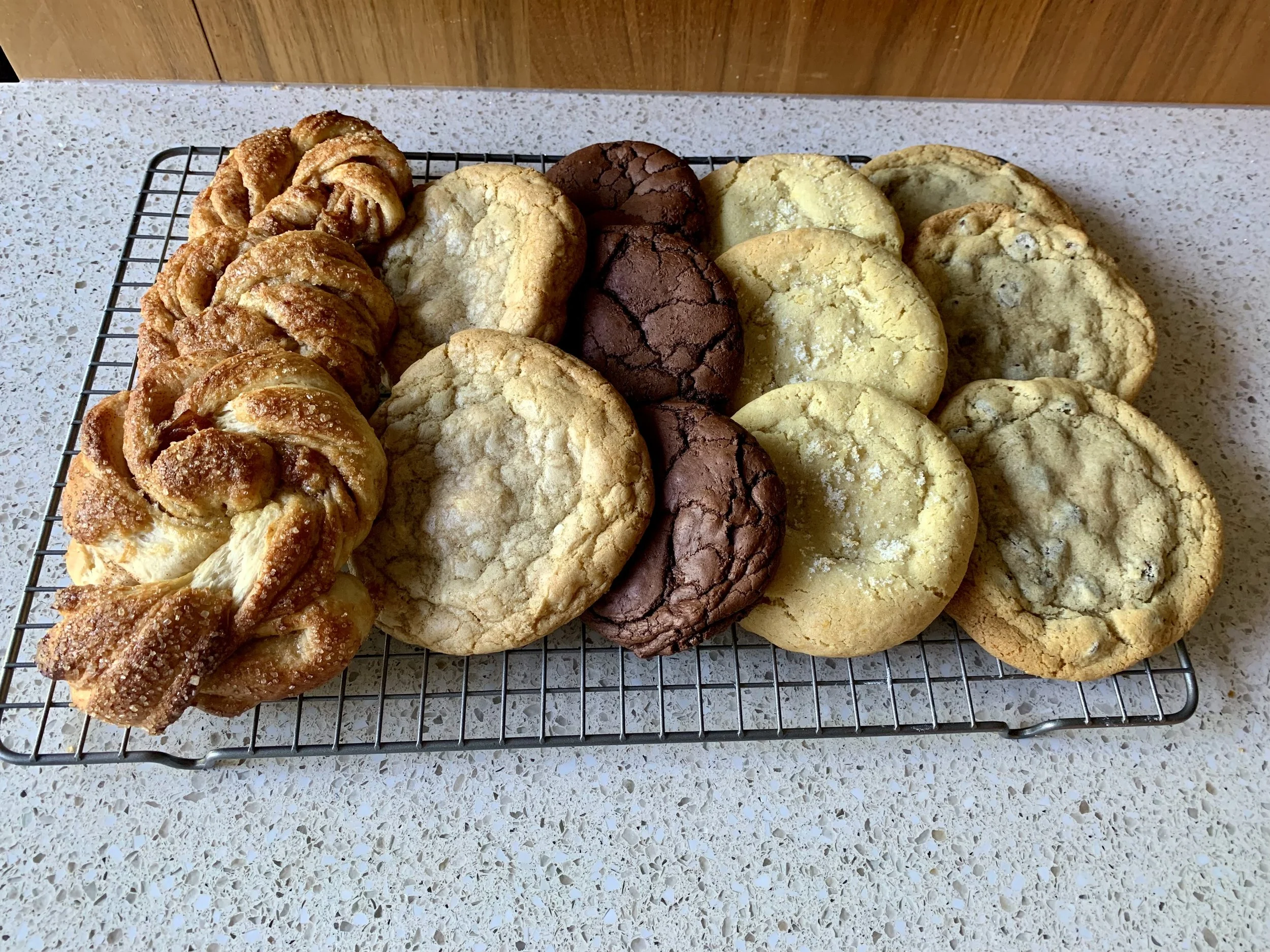 Assorted cookies and swedish cardamom buns on a cooling rack for a platter style service for lunch or group.