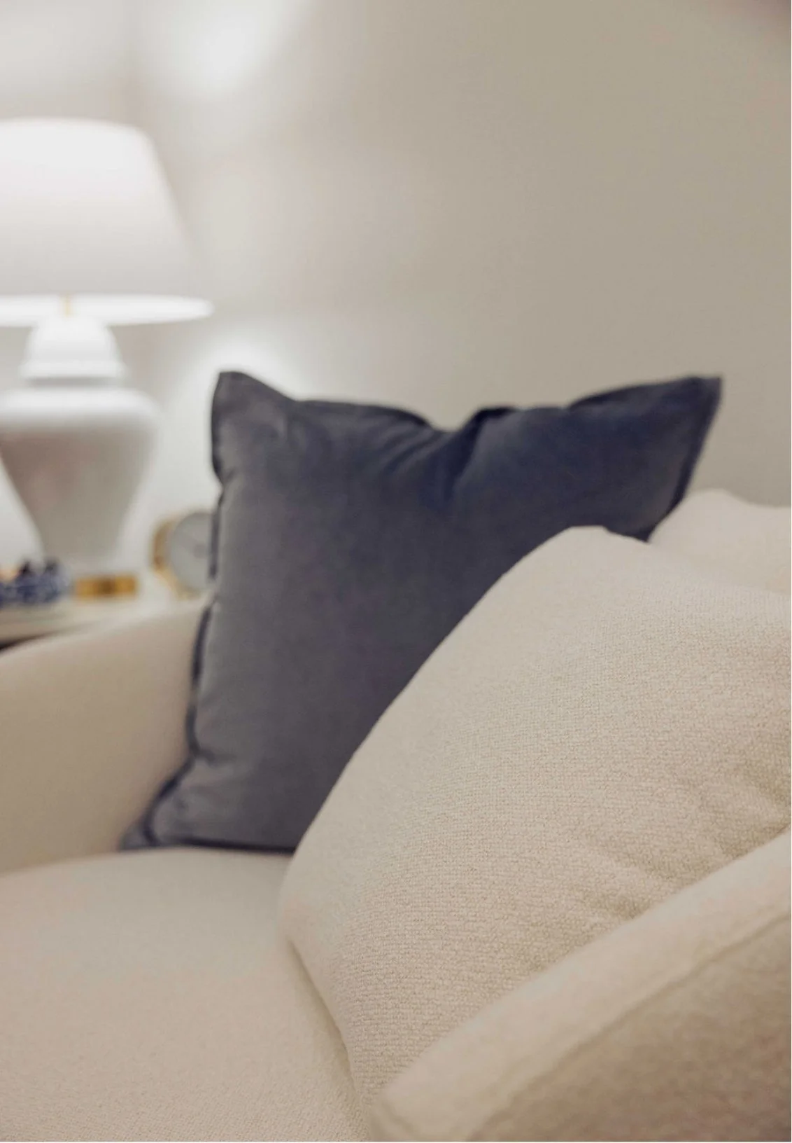 Close-up of a beige sofa in a Green Hills Nashville therapy office with two pillows, one black and one beige, and a blurred background with a white table lamp.