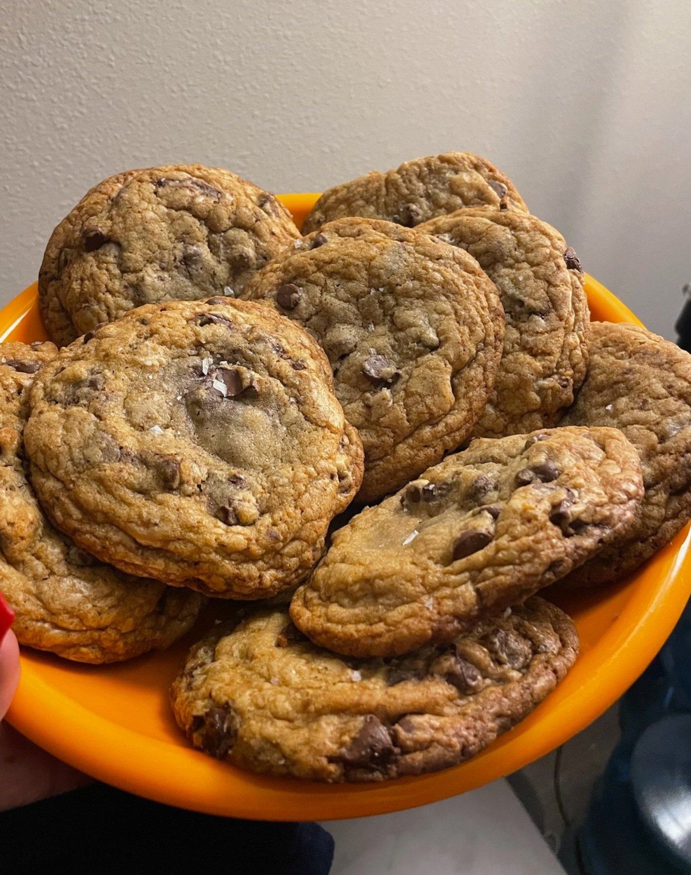 A plate of several freshly baked chocolate chip cookies on an orange dish.