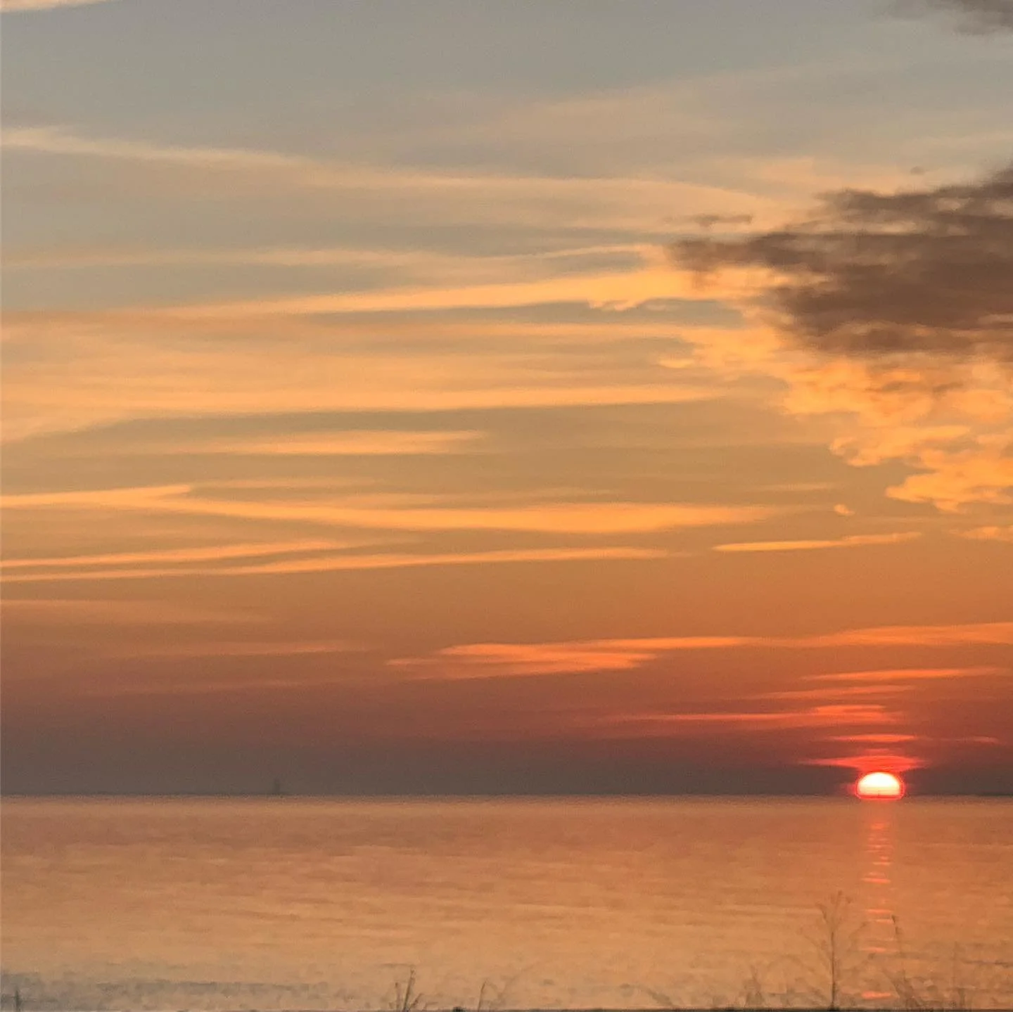 Sunset over water with colorful sky and some clouds.